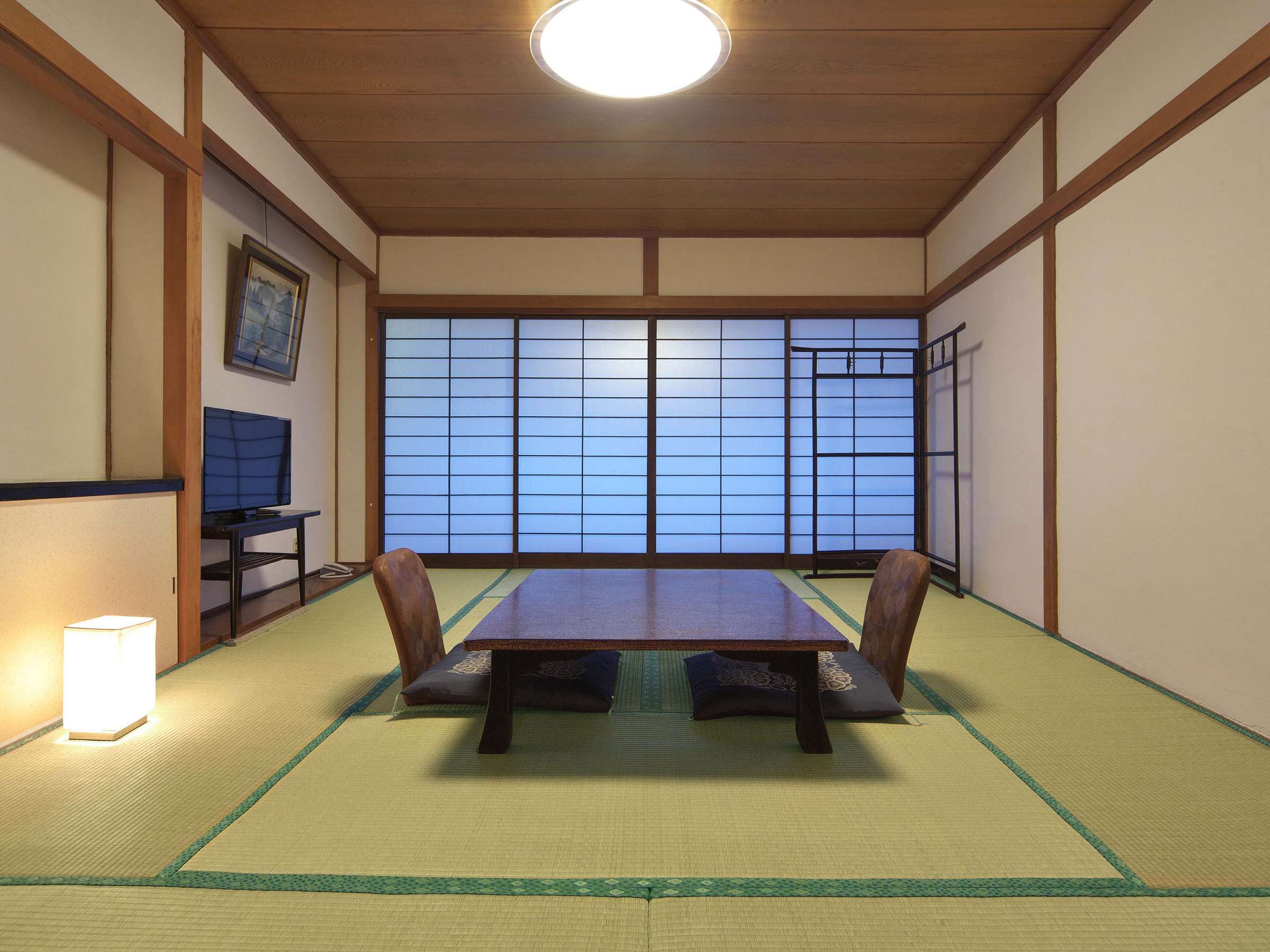 Bright tatami guest room with low table, floor chairs and a wide shoji screen