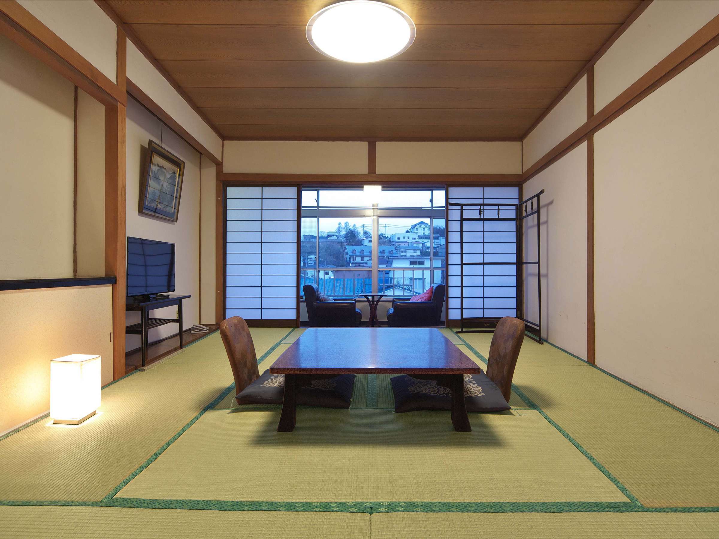 Tatami guest room with low table and a window overlooking the onsen town rooftops