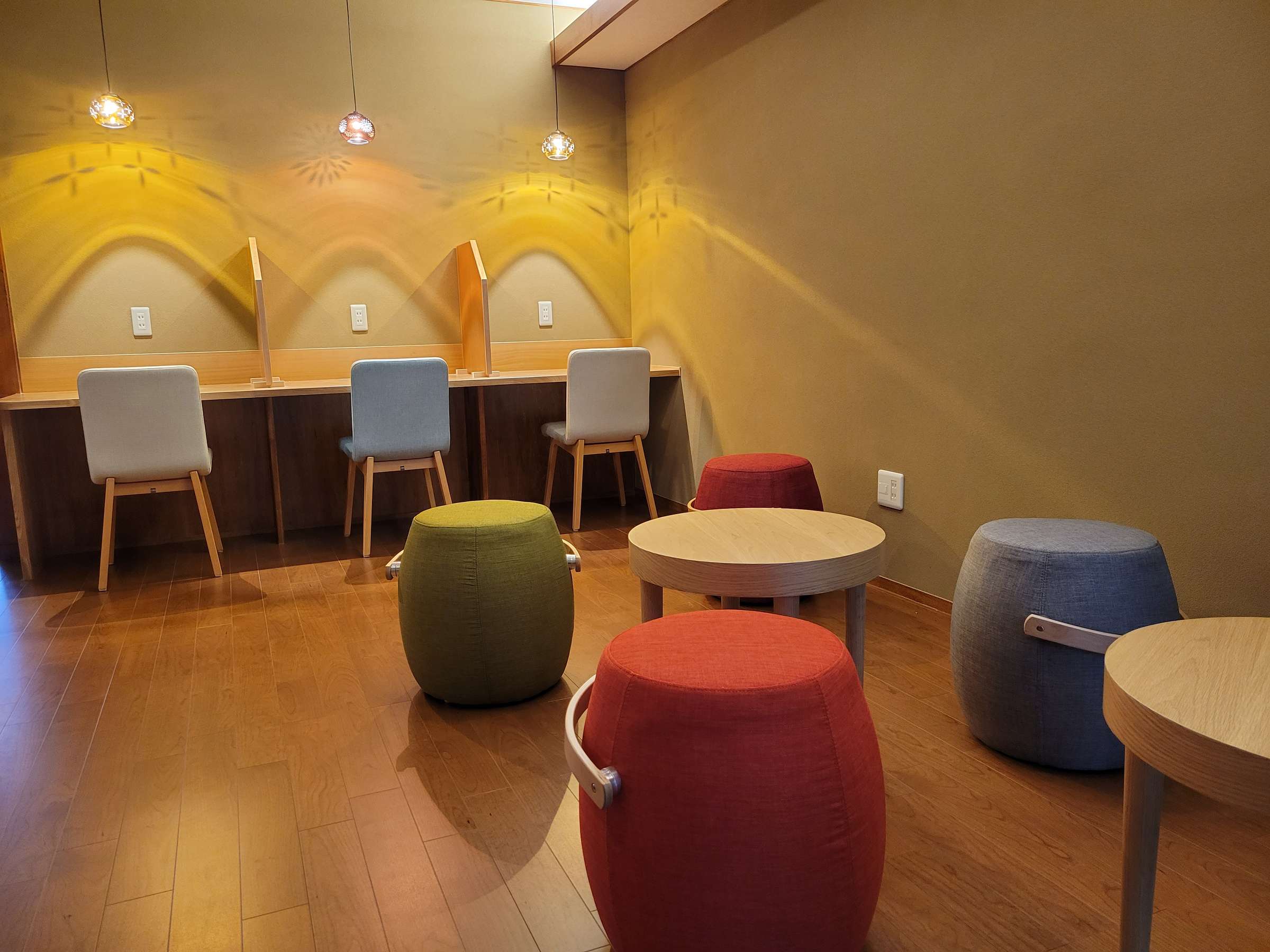 Relaxation lounge with colorful round stools and patterned pendant lamps over a vanity counter, Tsukimotoya, Kinosaki Onsen