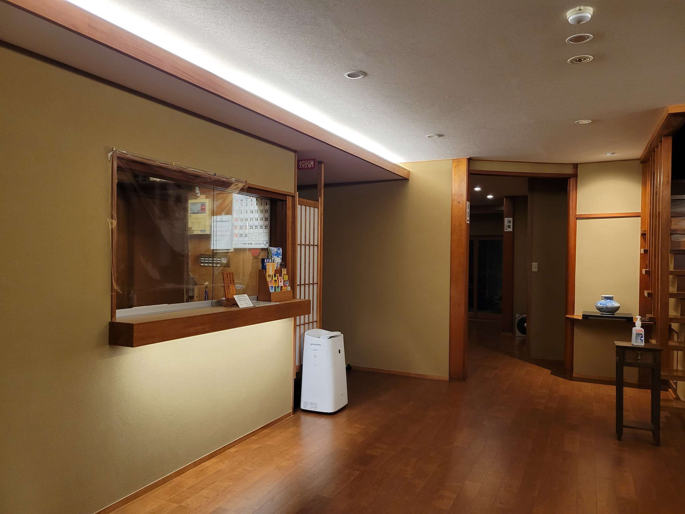 Wood-trimmed reception area with a glassed front desk and polished timber floor, Tsukimotoya, Kinosaki Onsen
