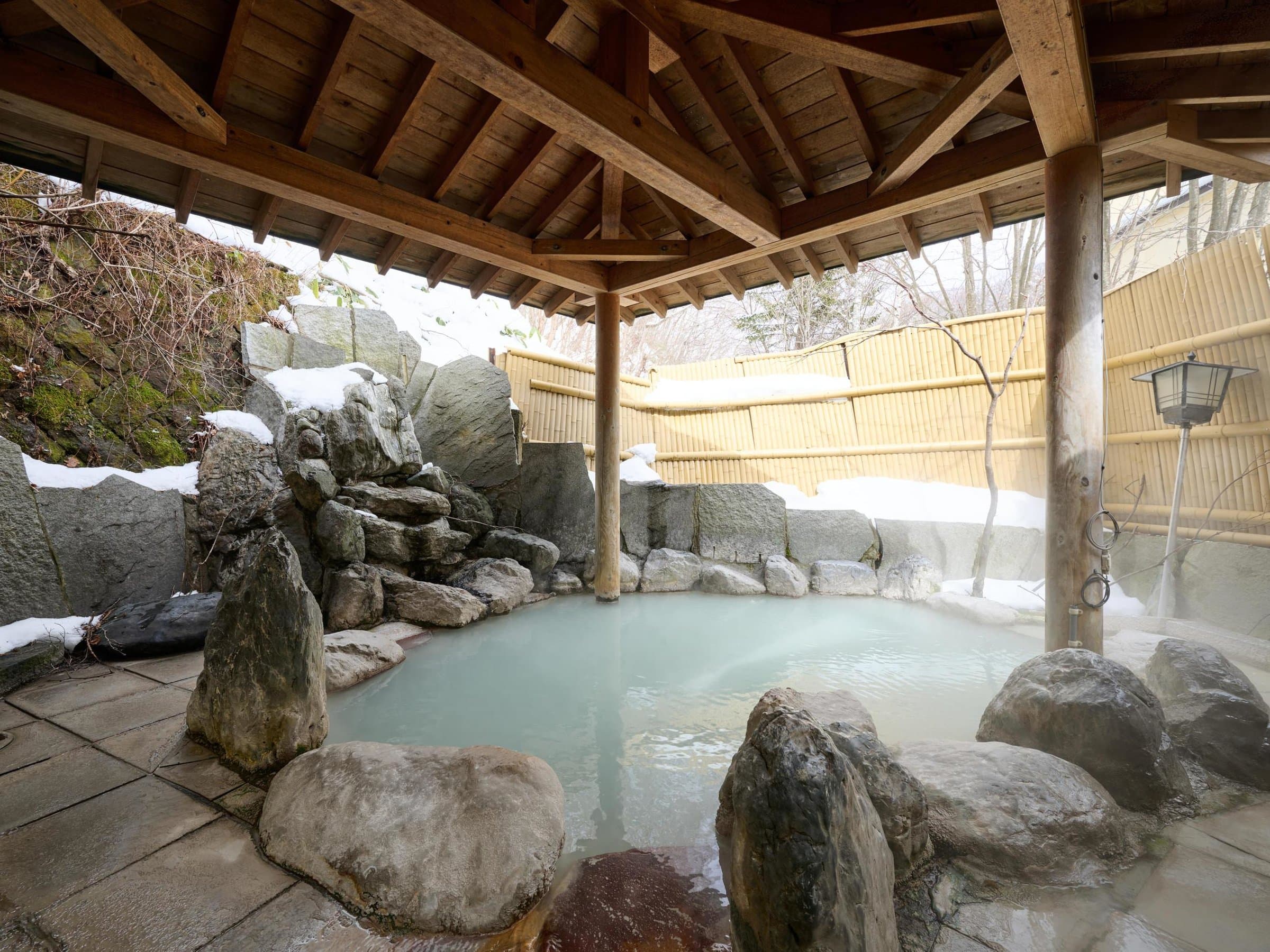 Open-air rotenburo bath with milky white hot spring water and snow-covered rocks at Oyado Kiyomizuya, Noboribetsu