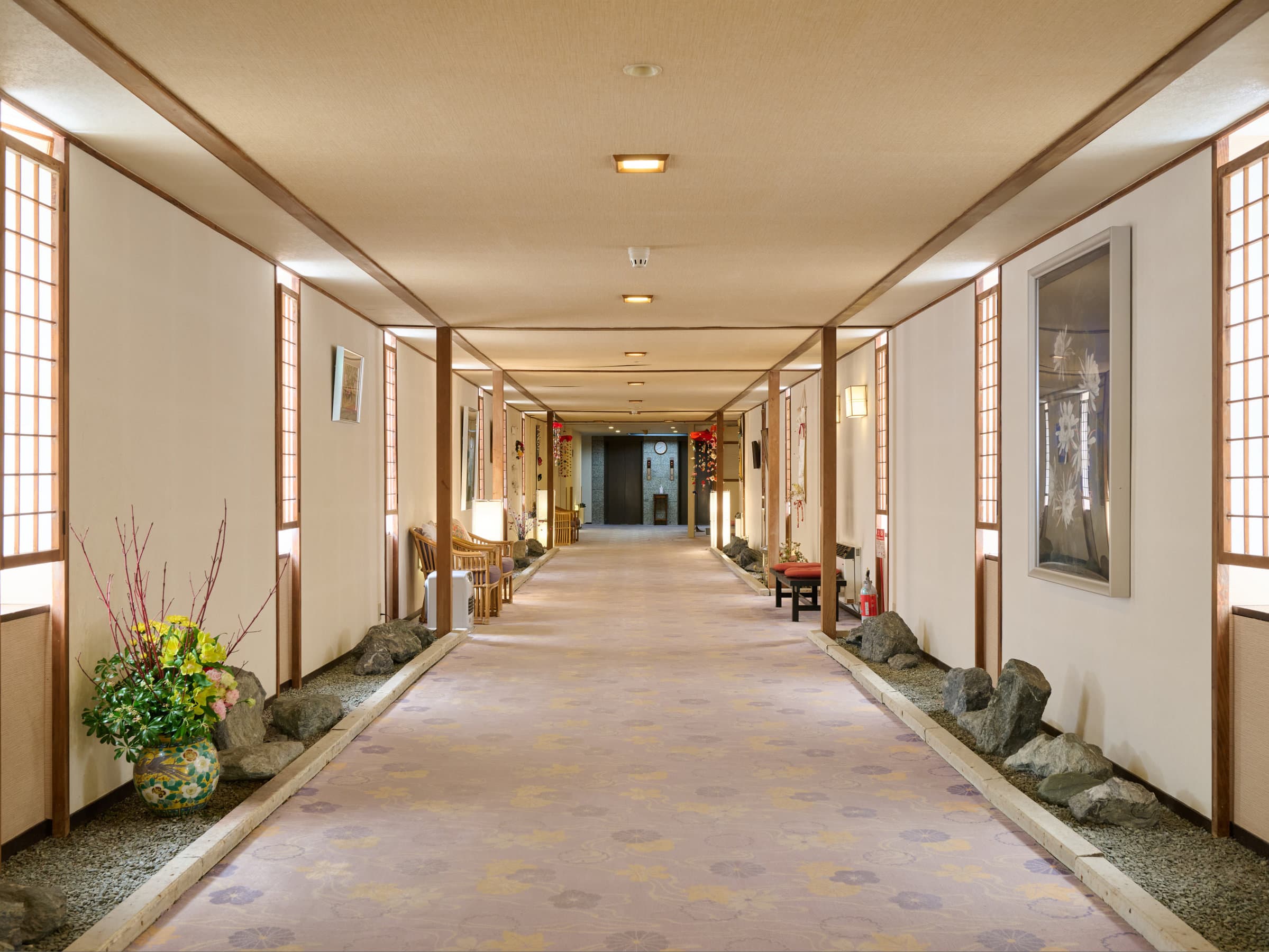 Long interior corridor with shoji screens, ikebana and stone accents at Oyado Kiyomizuya, Noboribetsu