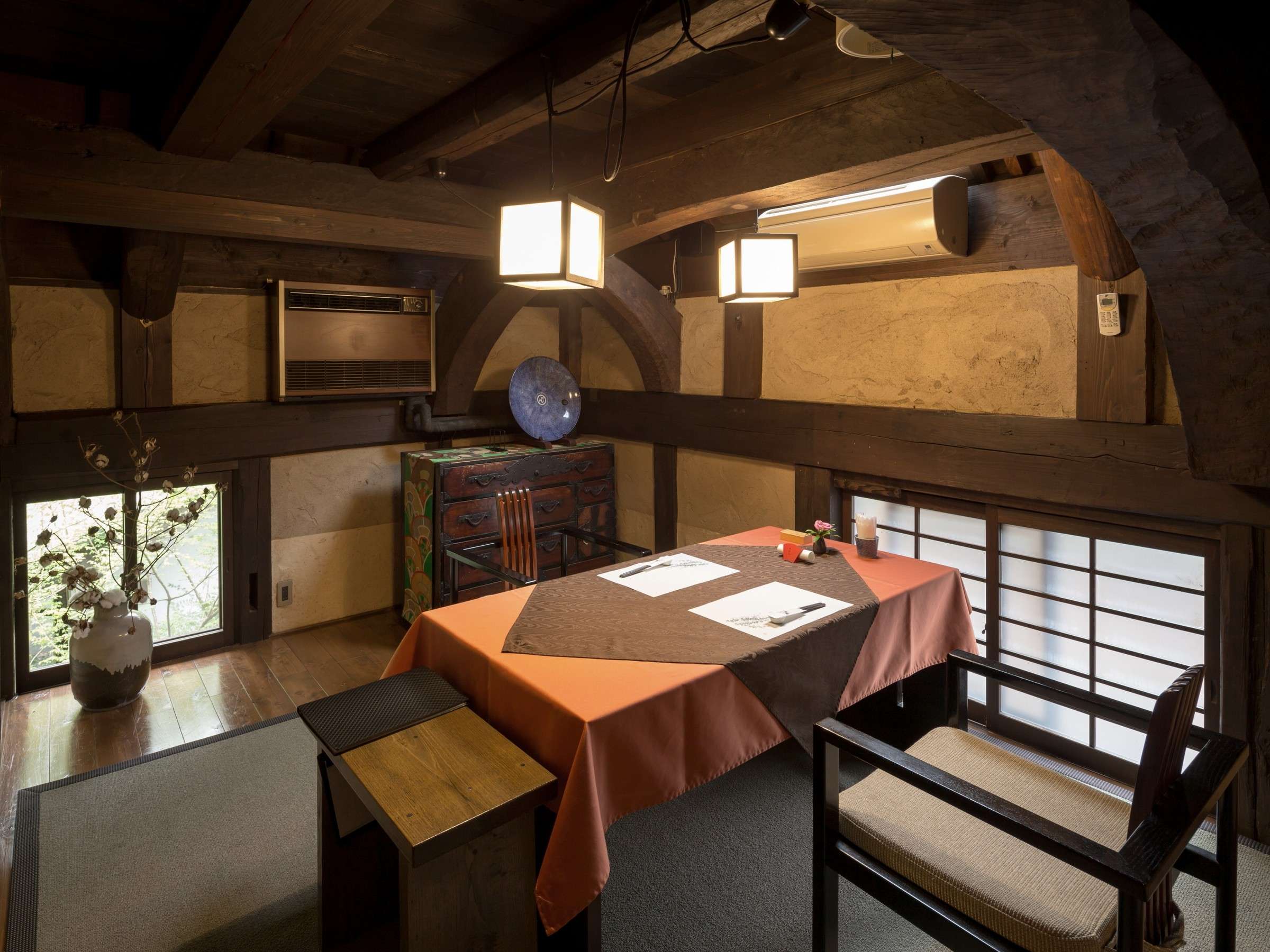 Private dining room at Satonoyu Waraku with a vaulted earthen-wall ceiling, antique chest and table set for two