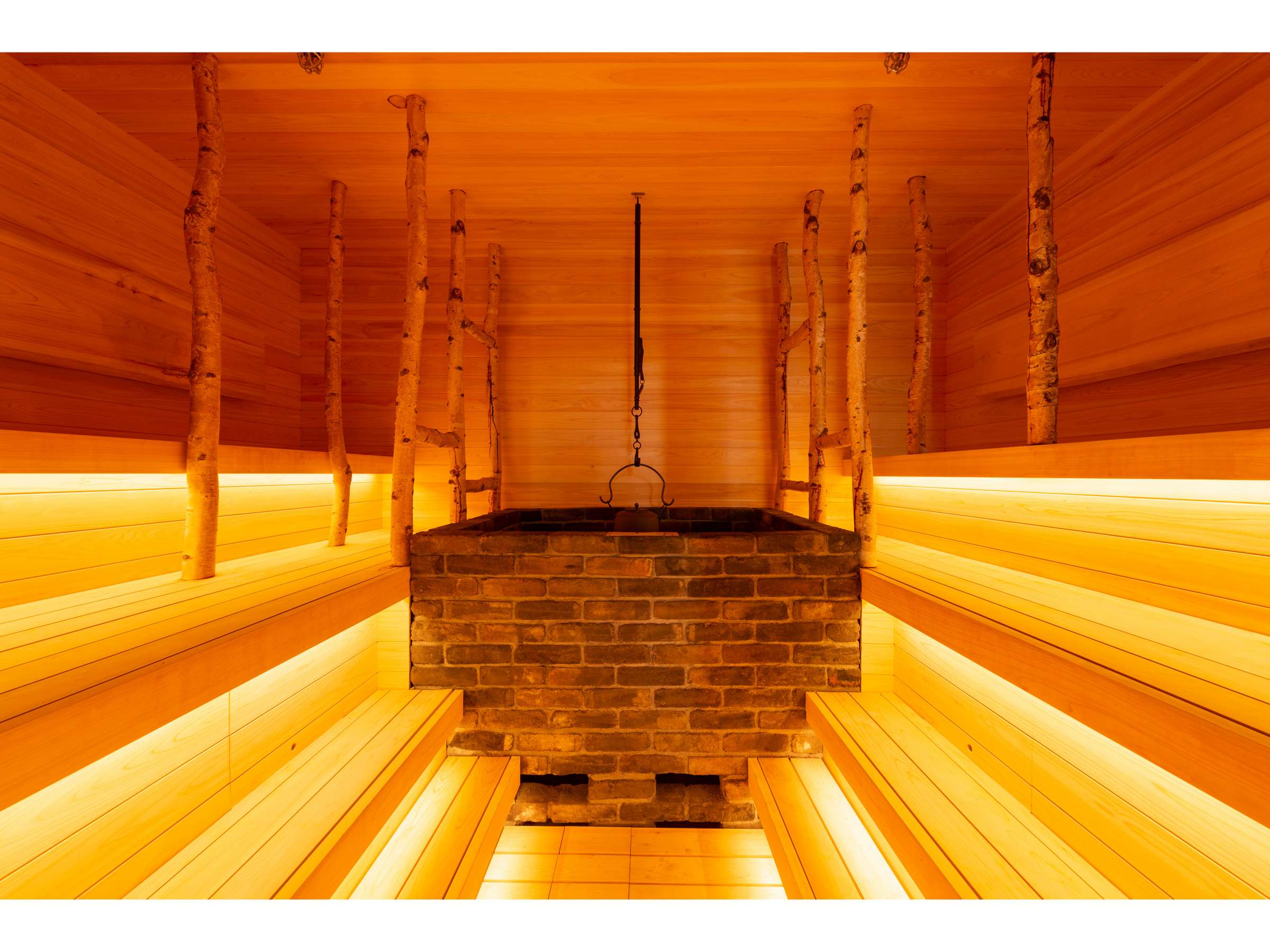 Wood-lined sauna with warm lighting and white birch posts at Noboribetsu Manseikaku, Noboribetsu Onsen