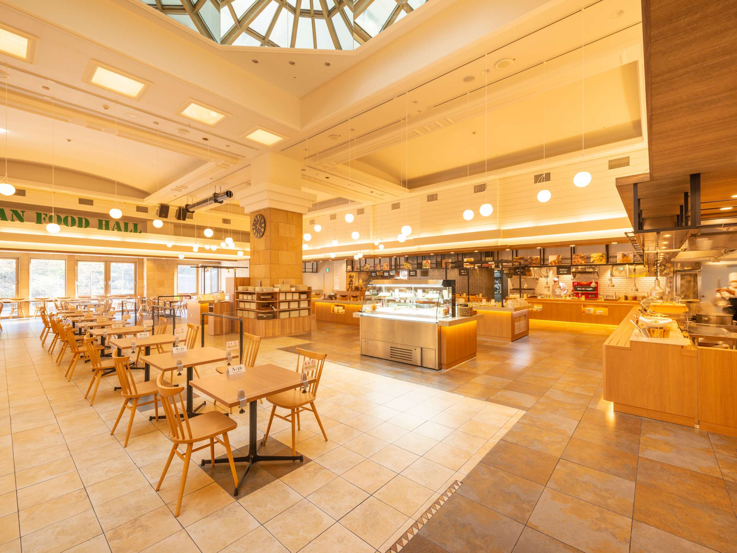Bright buffet food hall dining area with wooden tables and open kitchen counters at Noboribetsu Manseikaku