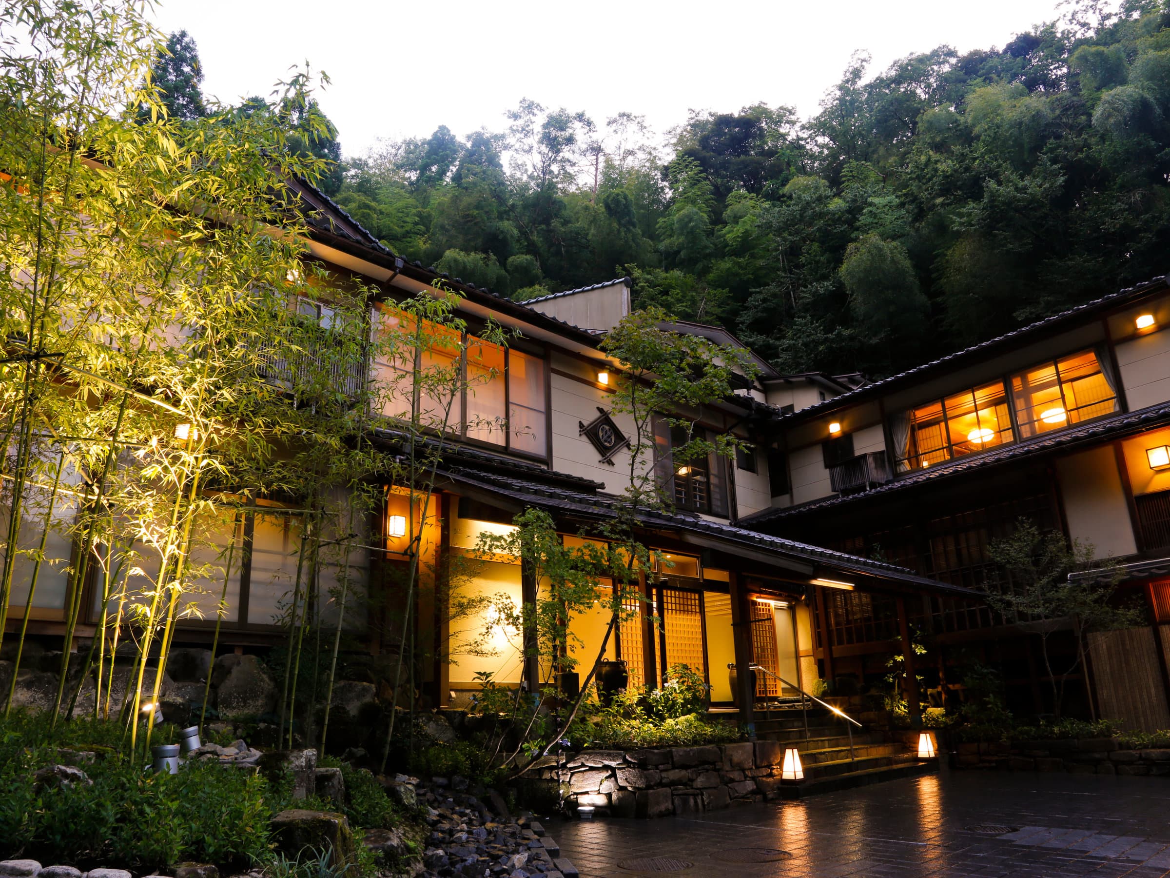 Yuraku Kinosaki Spa & Gardens main building exterior lit at dusk with bamboo grove