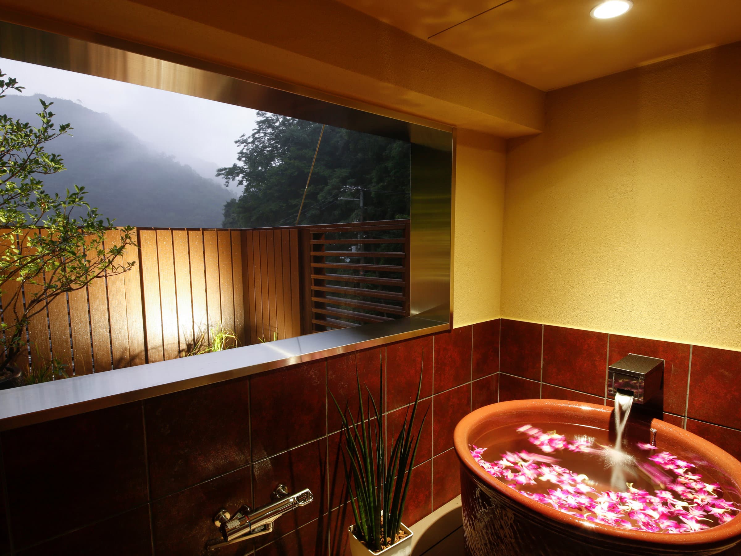 Yuraku Kinosaki private in-room bath with flower petals floating, garden view through window