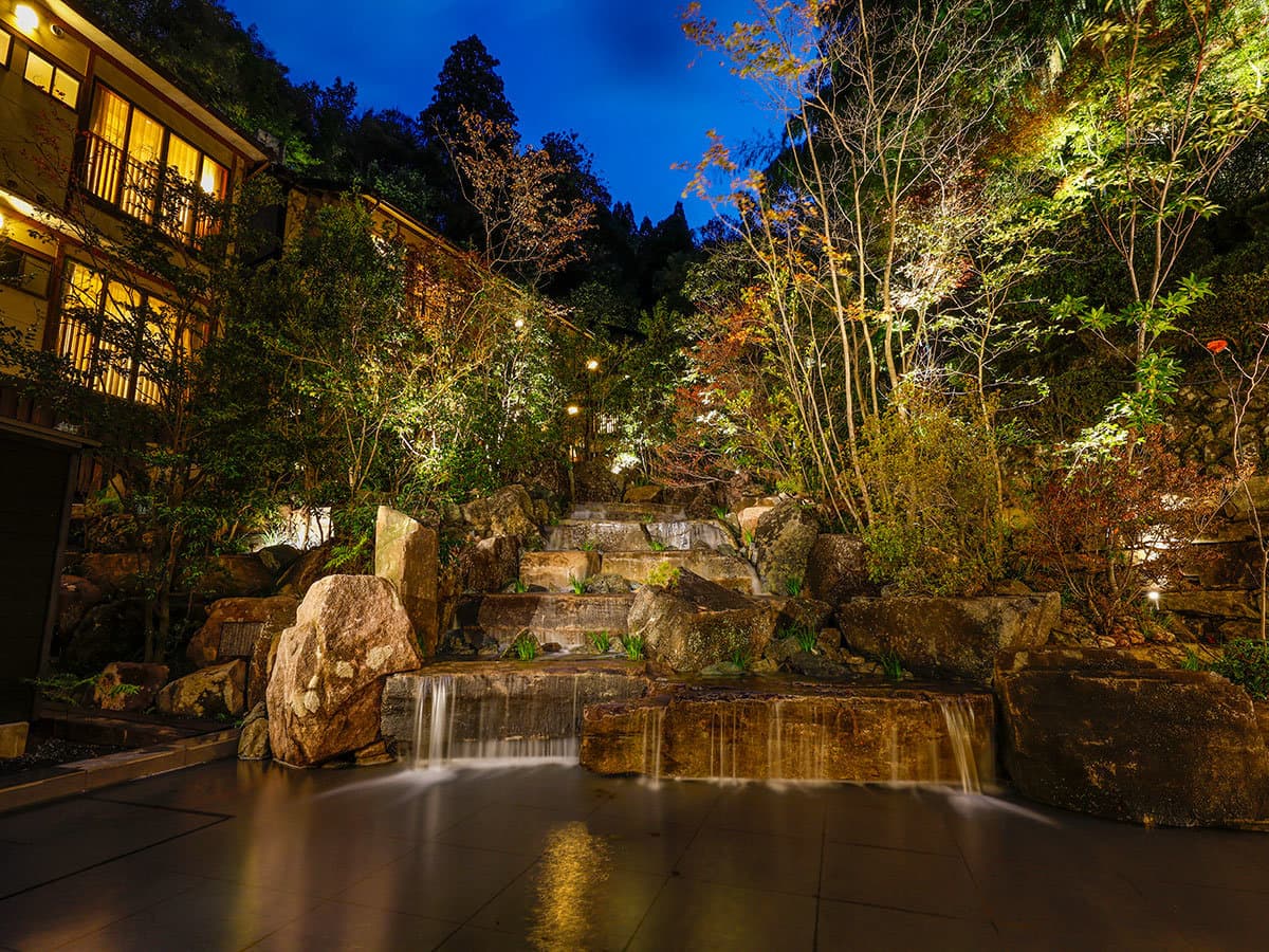 Yuraku Kinosaki illuminated garden waterfall and stone landscaping beside the inn at night