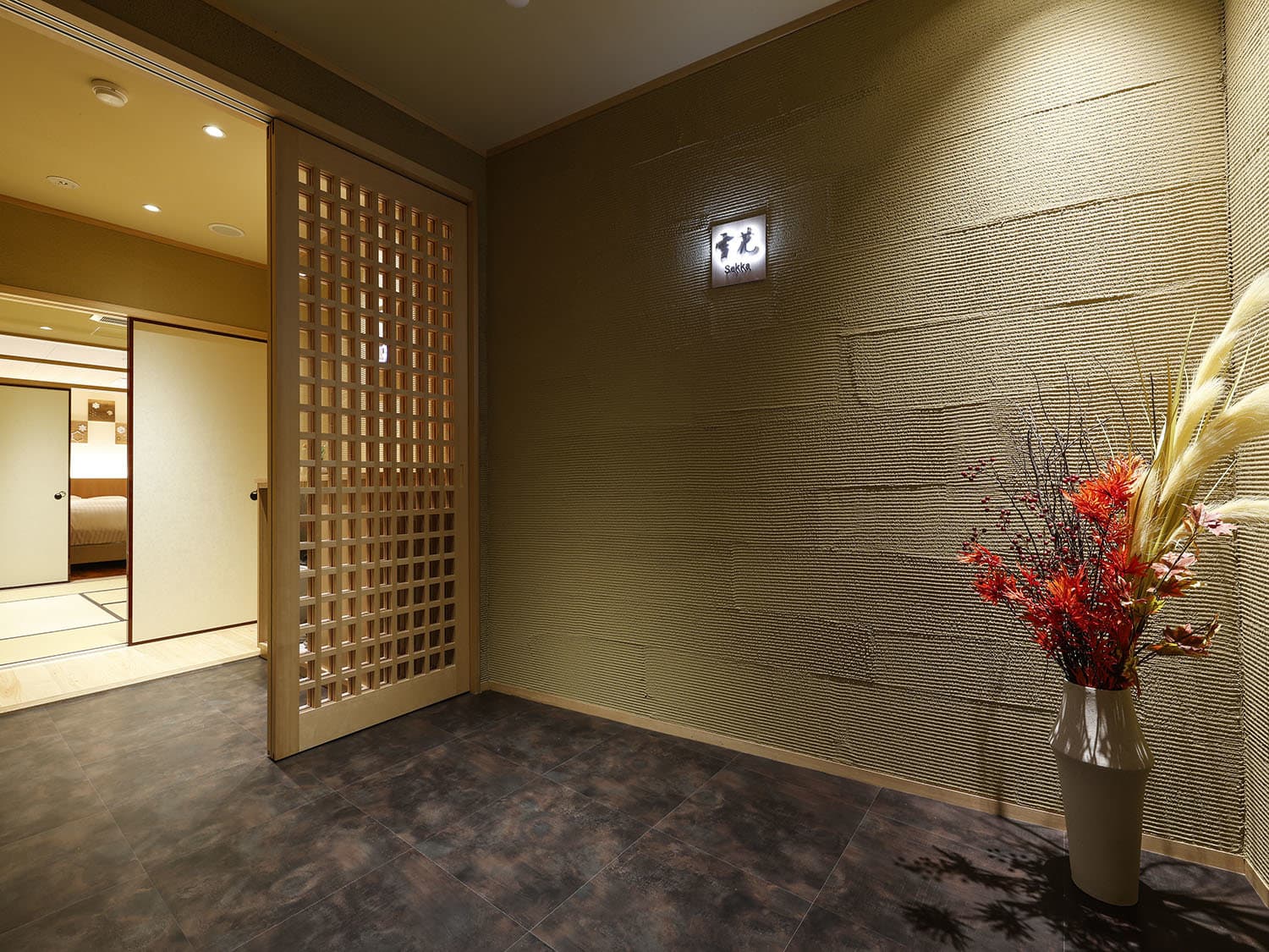 Yuraku Kinosaki guest room entrance hallway with lattice door and seasonal flower arrangement
