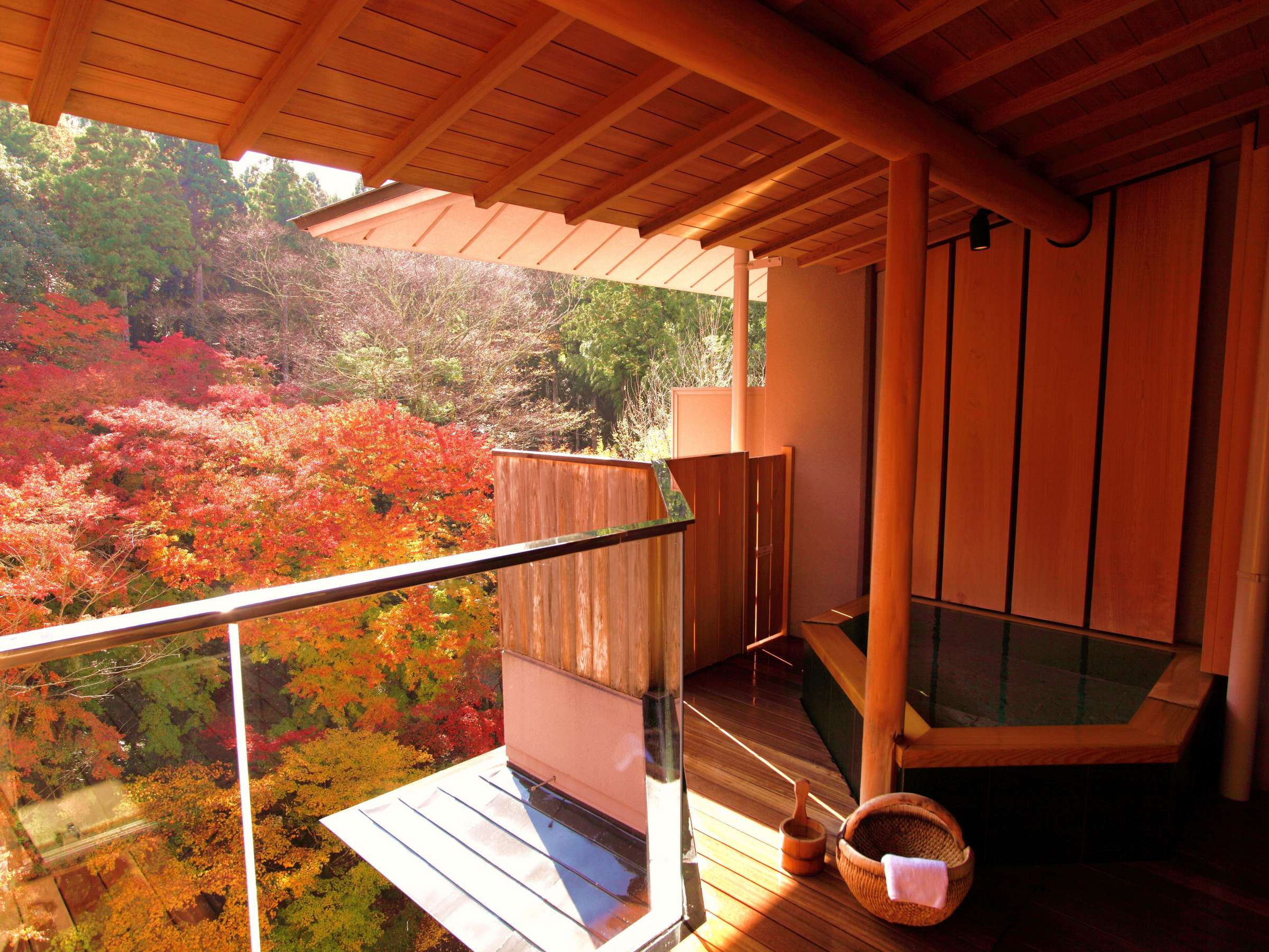 Private in-room open-air cypress bath on a wooden deck overlooking vivid autumn foliage at SORA Togetsuso Kinryu, Izu