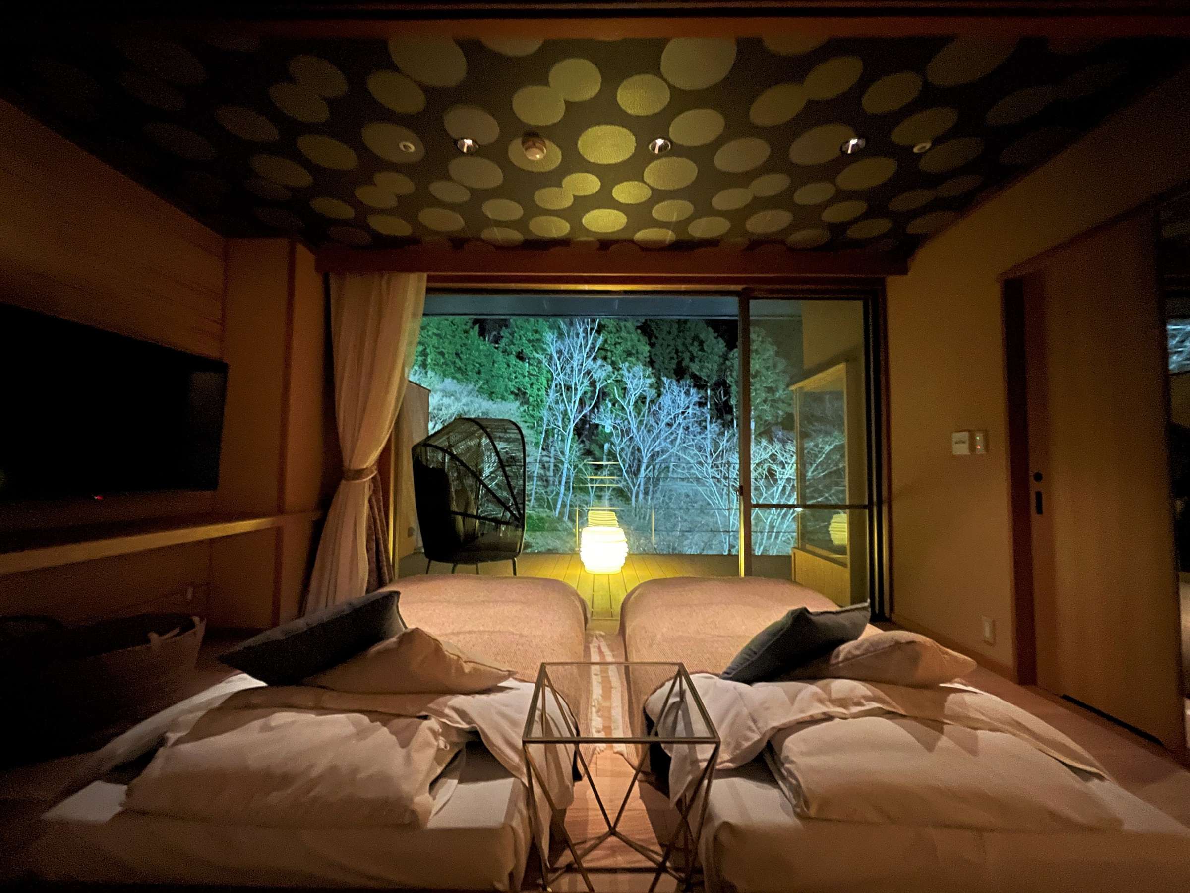 Modern Japanese guest room with twin low beds, lattice ceiling and illuminated garden view at night, SORA Togetsuso Kinryu, Shuzenji