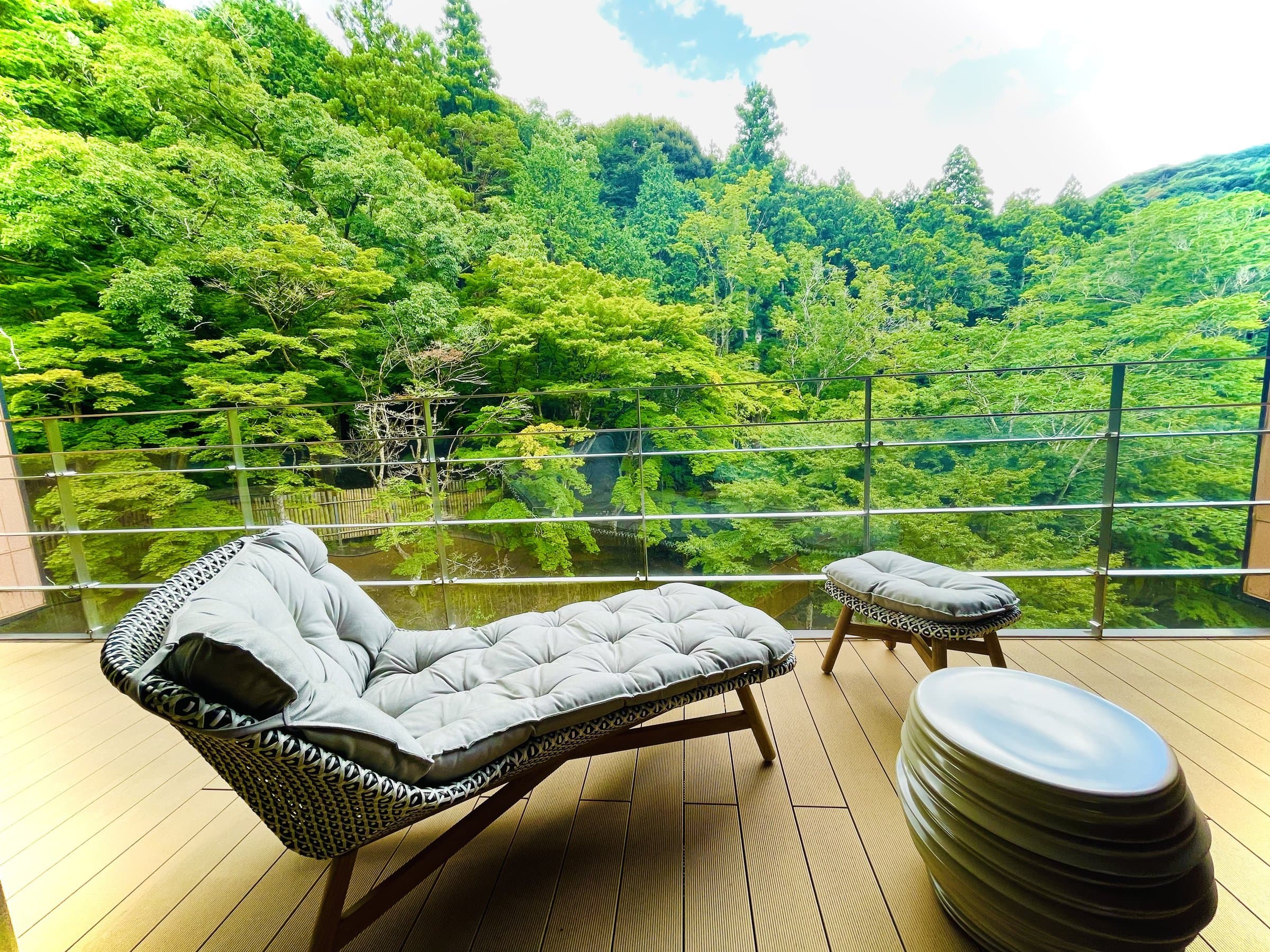 Open-air wooden balcony lounge with chaise overlooking a lush green wooded valley at SORA Togetsuso Kinryu, Shuzenji Onsen, Izu