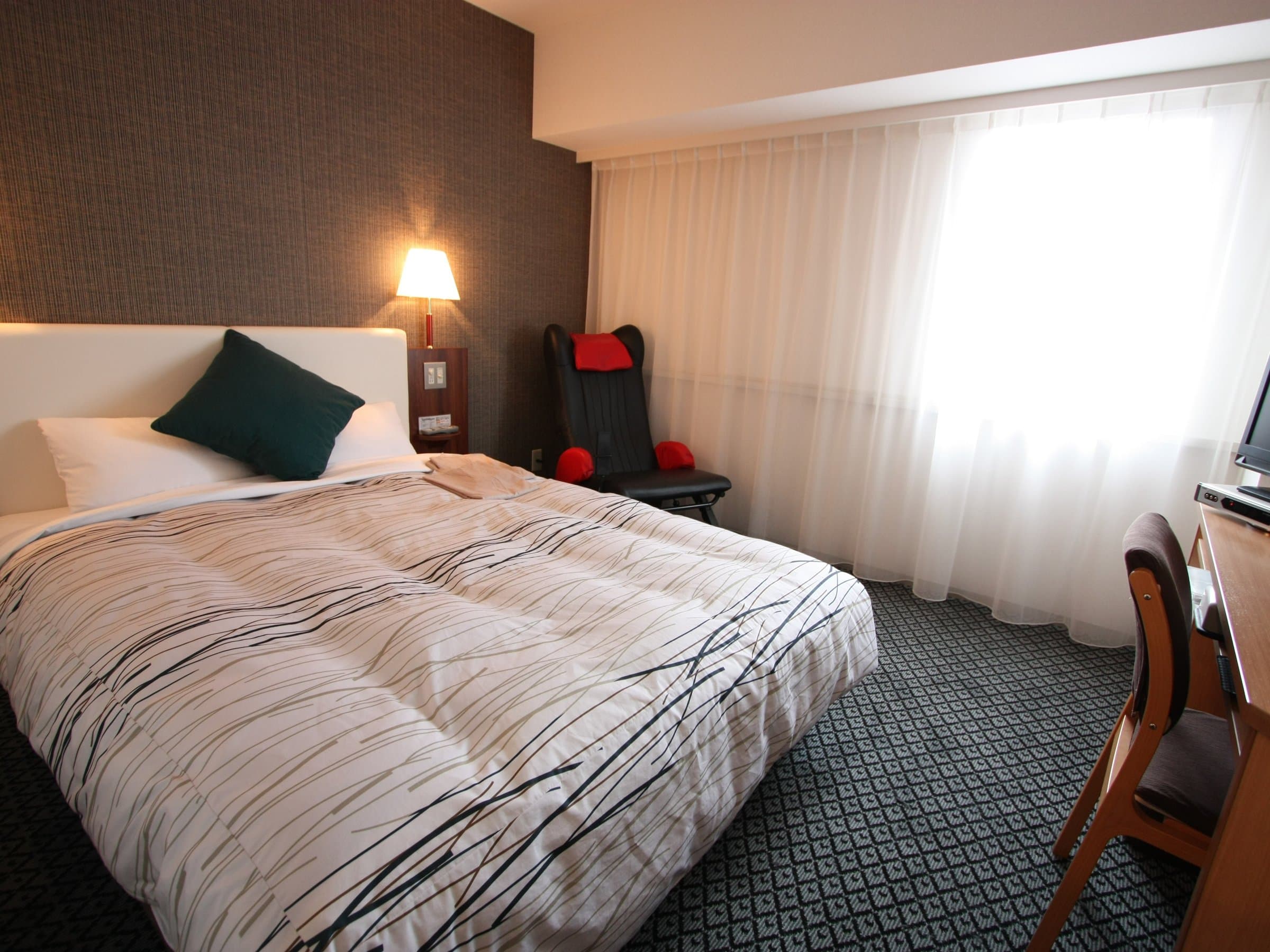 Double room with massage chair and patterned carpet at Kanazawa Manten Hotel Ekimae