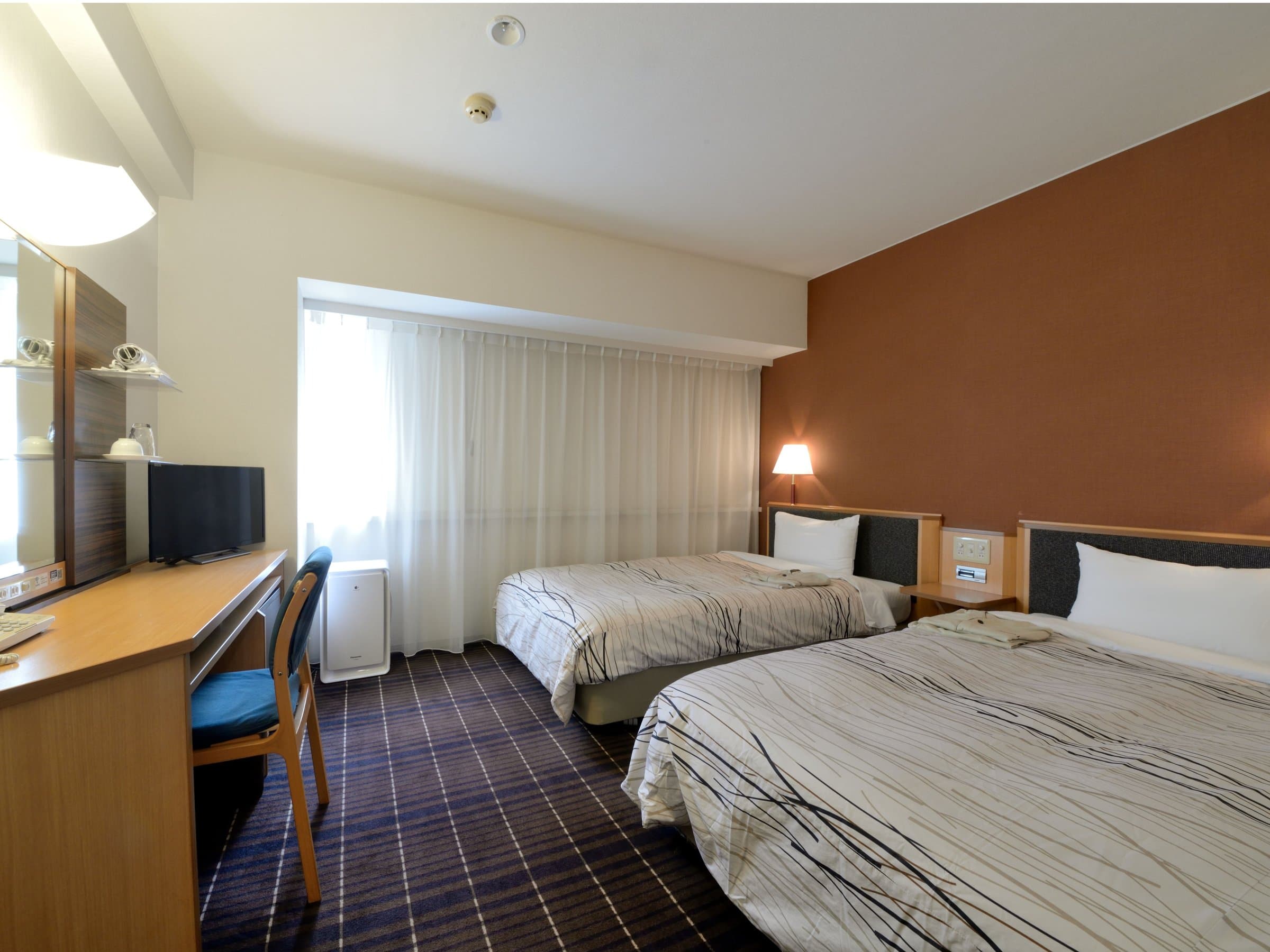 Twin guest room with two beds and accent wall at Kanazawa Manten Hotel Ekimae