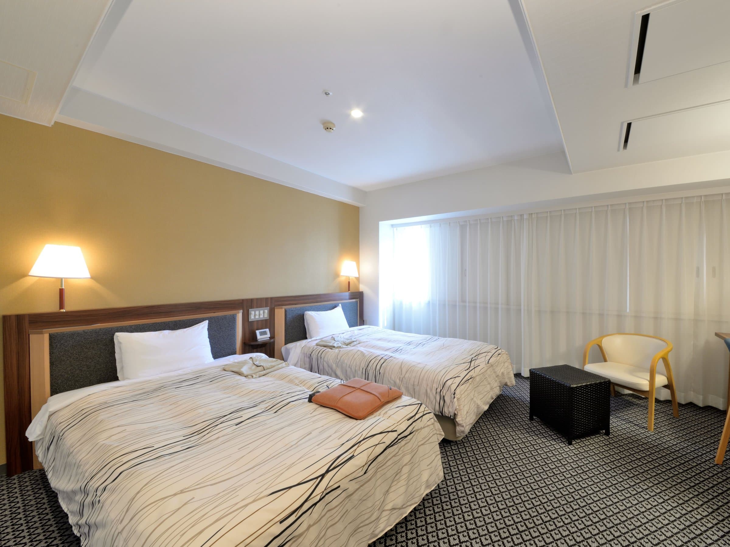 Spacious superior twin room with two beds and lounge chair at Kanazawa Manten Hotel Ekimae