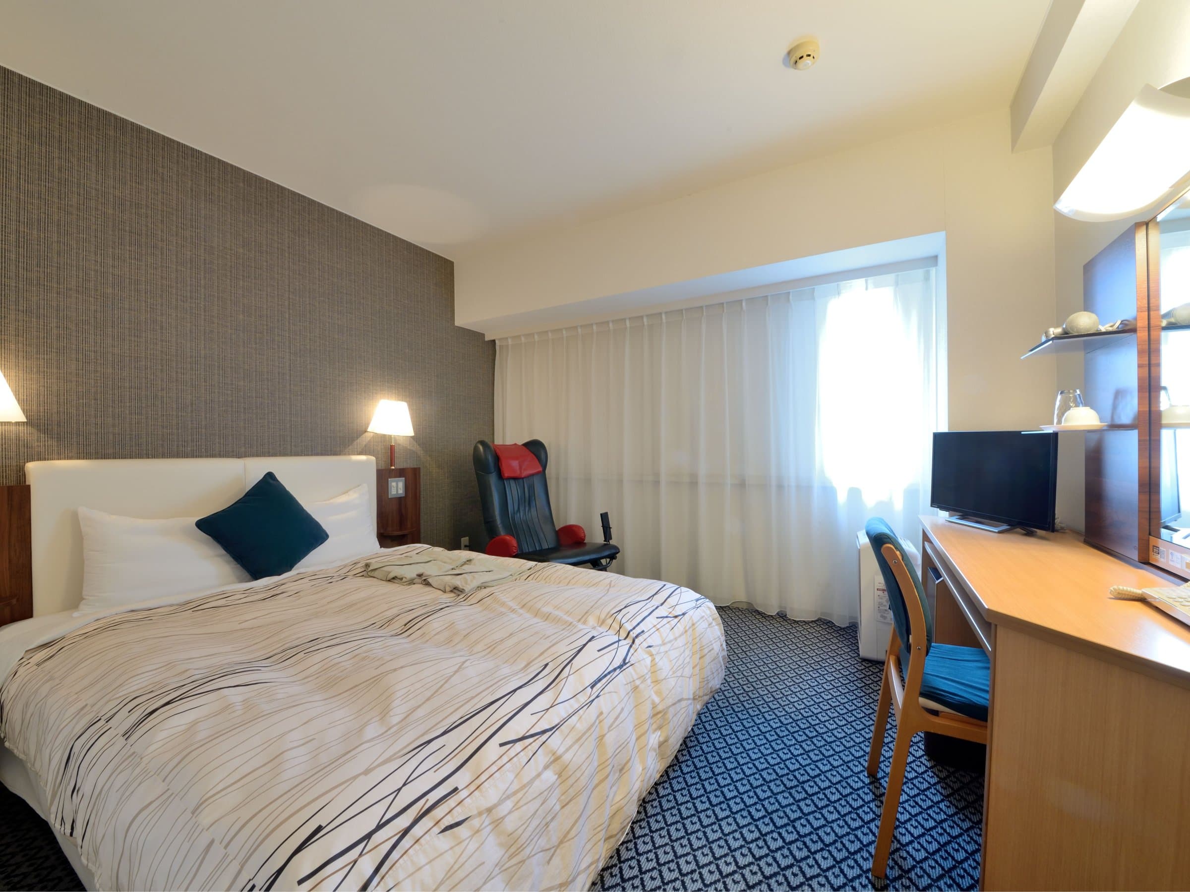 Bright double room with desk and massage chair at Kanazawa Manten Hotel Ekimae