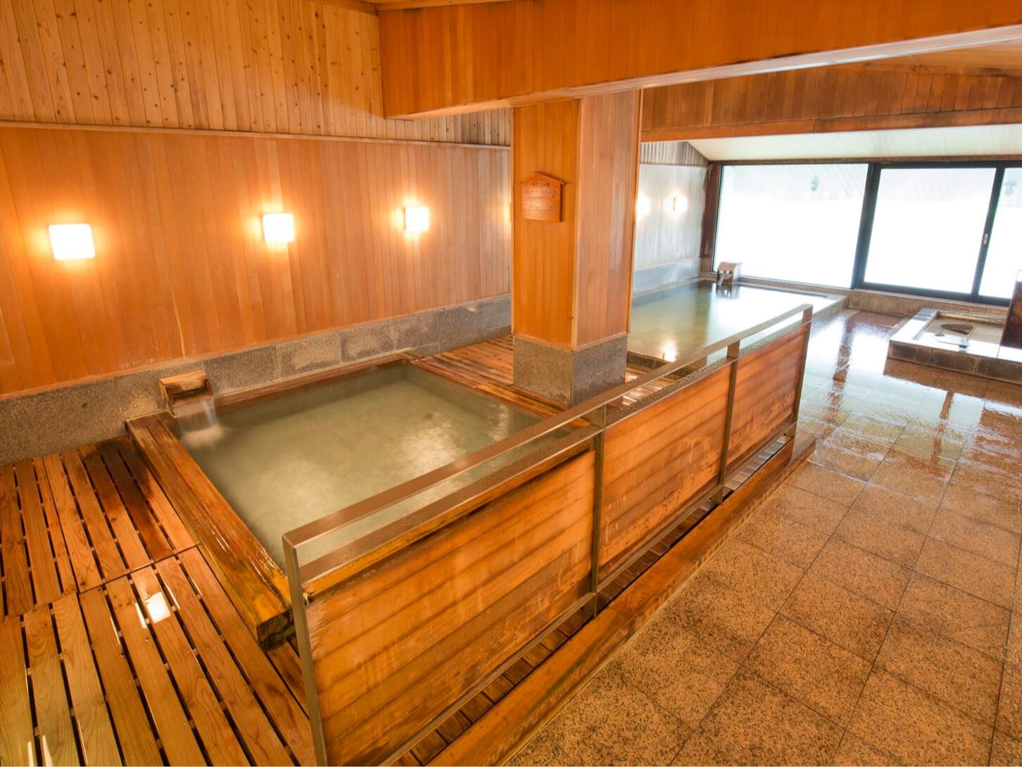 Spacious wood-lined indoor public bath at Hotel Jurin in Zao Onsen with stone flooring and large windows