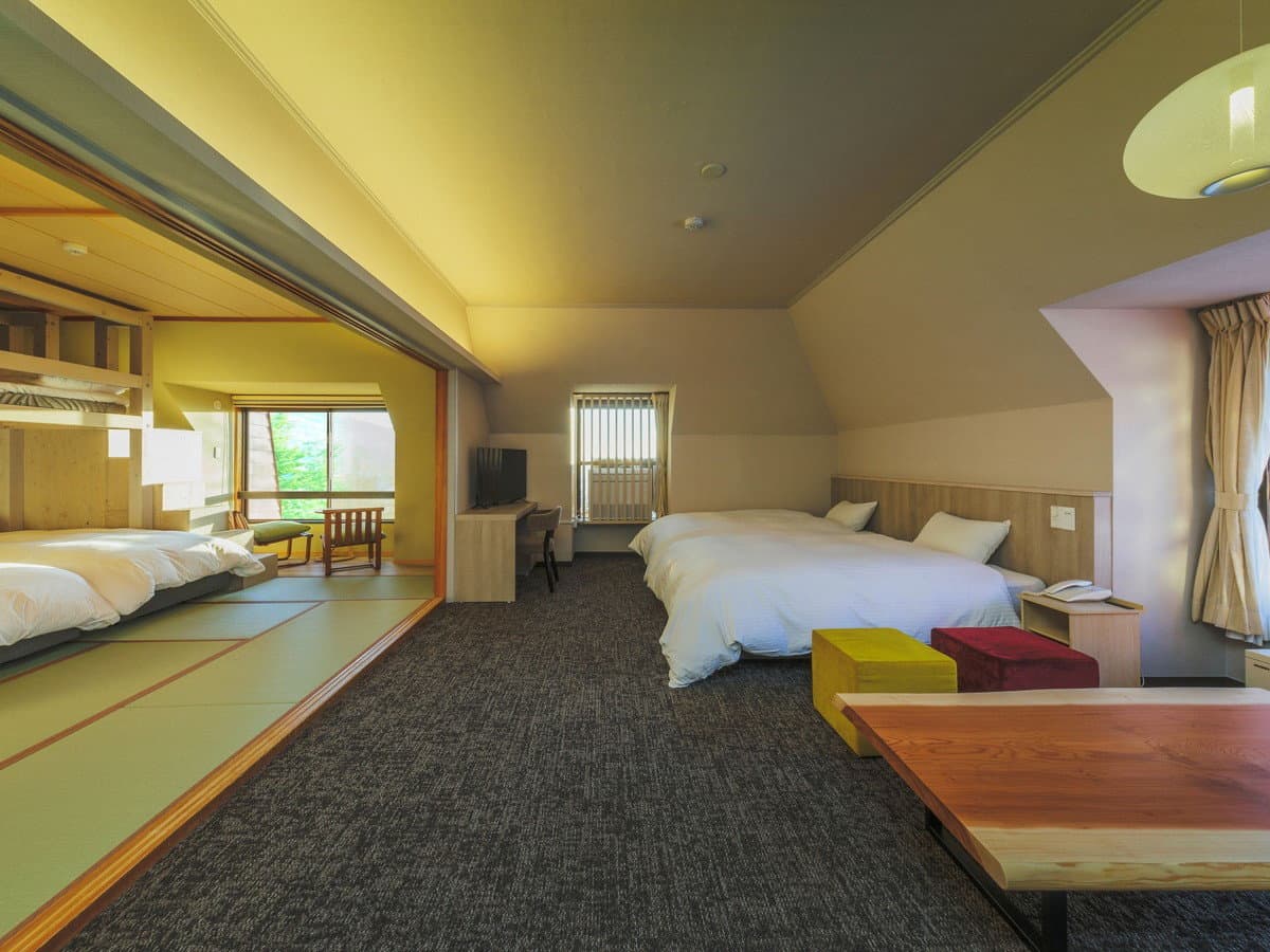 Combined Japanese-Western room at Hotel Jurin with twin beds beside a tatami area open to a forest view