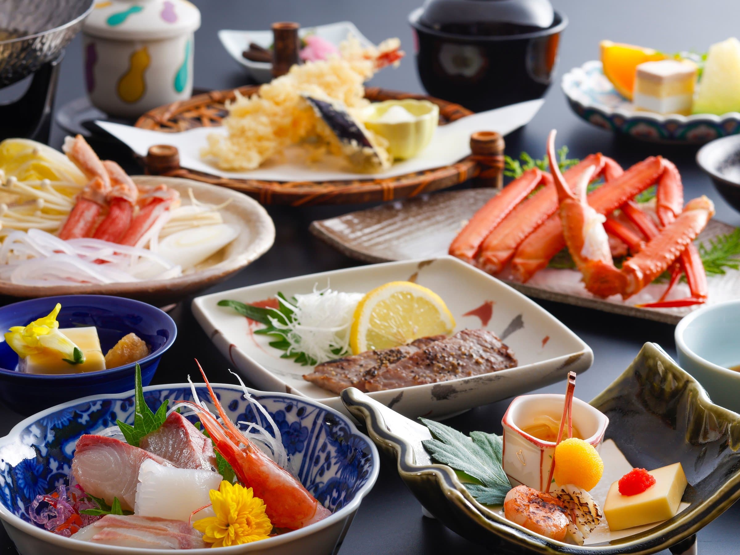 Full kaiseki dinner spread of snow crab, tempura and sashimi on individual dishes, Yamamotoya, Kinosaki Onsen