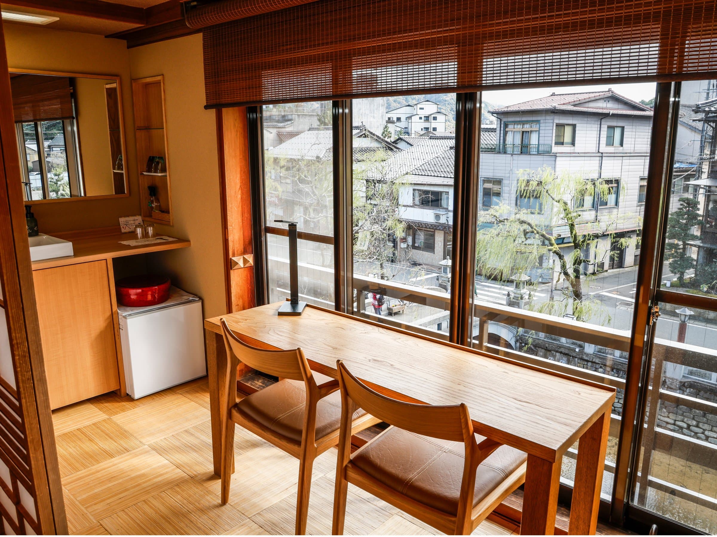 Modern Japanese-Western room with a wooden table overlooking the willow-lined onsen street, Yamamotoya, Kinosaki Onsen