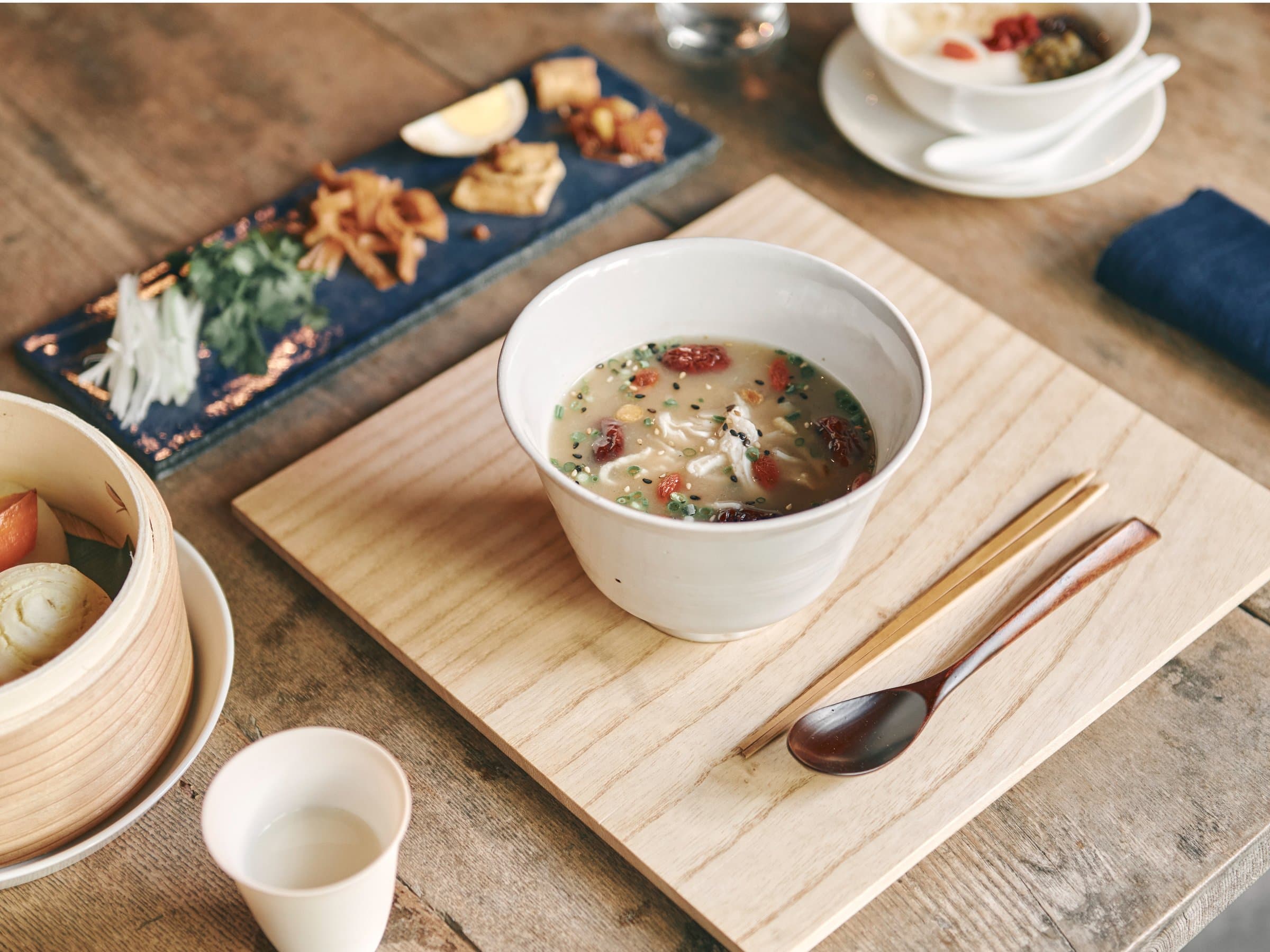 Japanese rice porridge breakfast set on a wooden board with side dishes and a bamboo steamer at Korinkyo Kanazawa