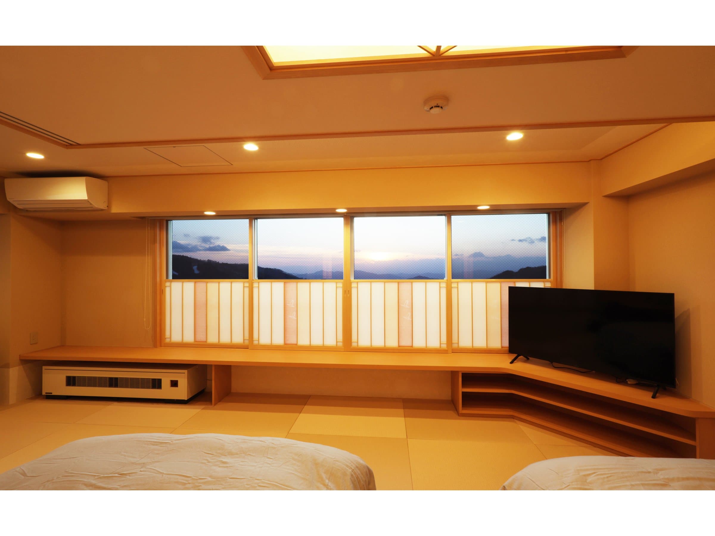 Guest room interior at dusk with low window seating overlooking the Zao mountains at sunset