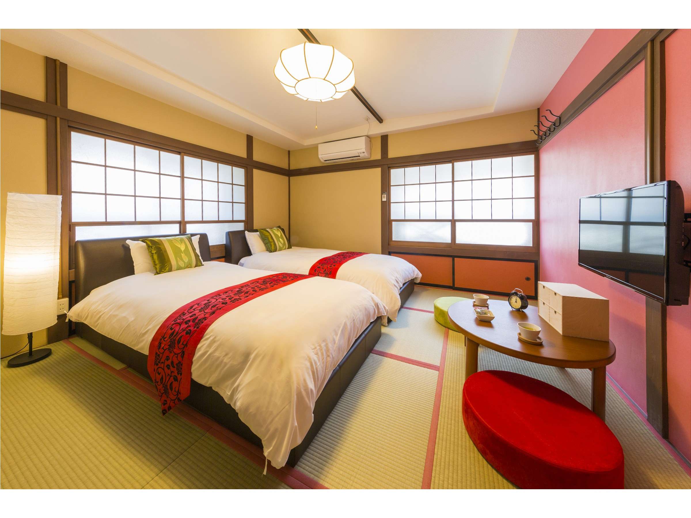 Cozy tatami room with two beds, red accent wall and round red floor cushions