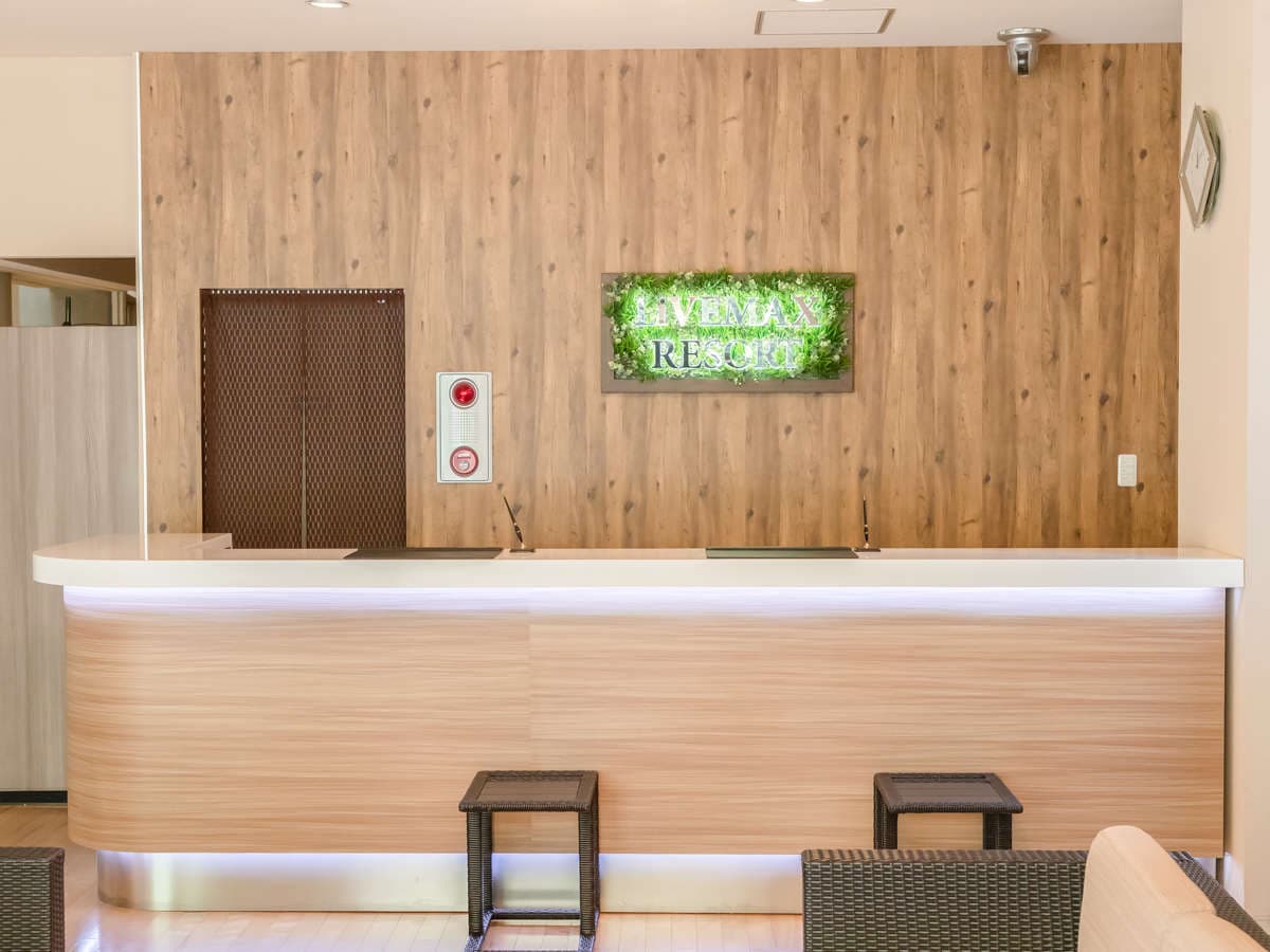 Reception desk with a wood-panel wall and a moss-lettered resort sign