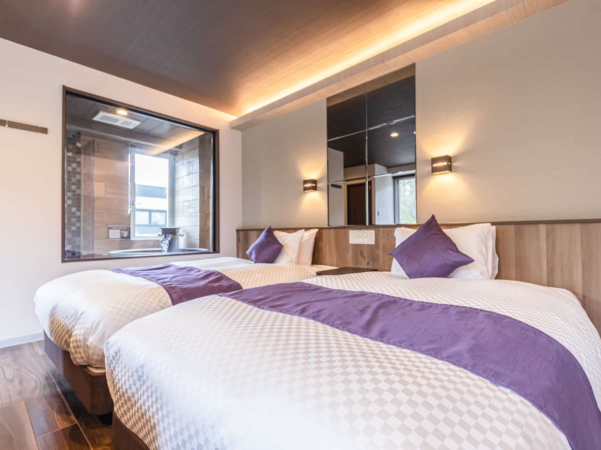 Suite twin bedroom with an interior window opening onto the in-room Shigaraki-ware bath