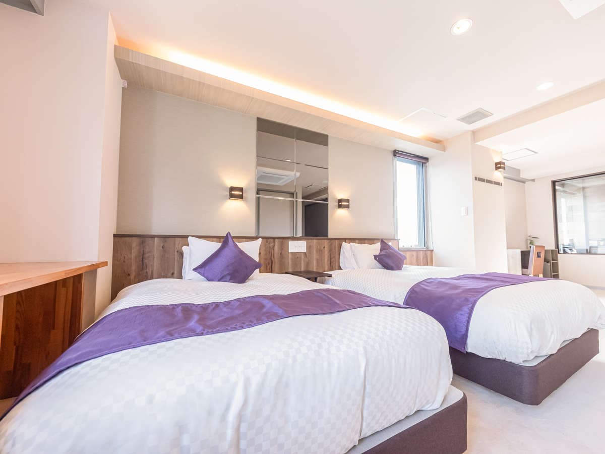 Spacious junior-suite twin guest room with warm indirect lighting and wood accents