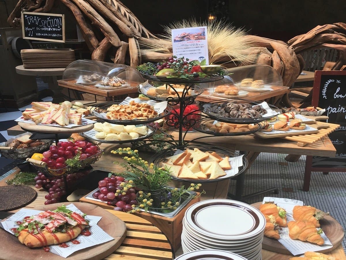 Breakfast buffet spread of breads, waffles, cheeses, grapes and pastries on rustic wooden stands