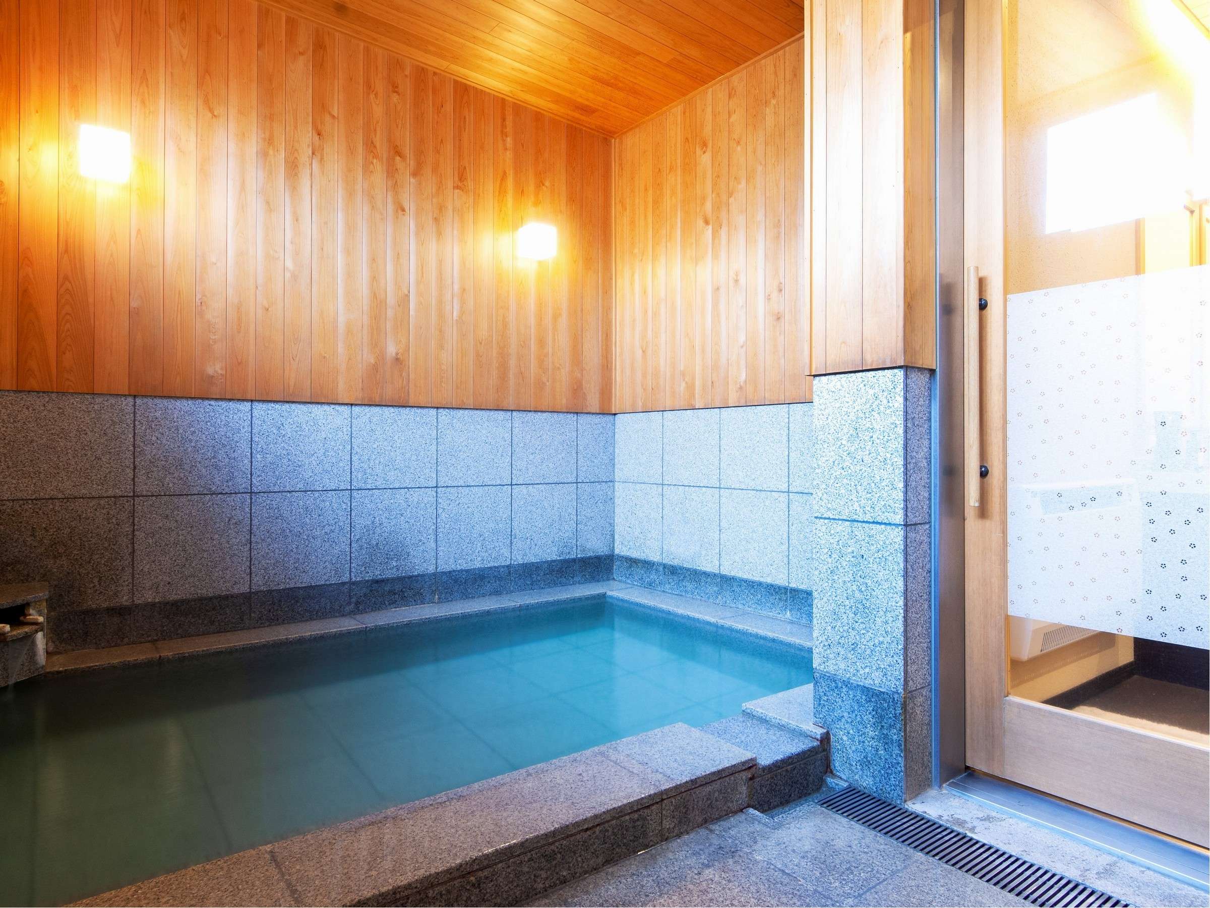 Oyado Yukizumi indoor onsen bath with cedar ceiling, stone-tiled walls and pale blue spring water