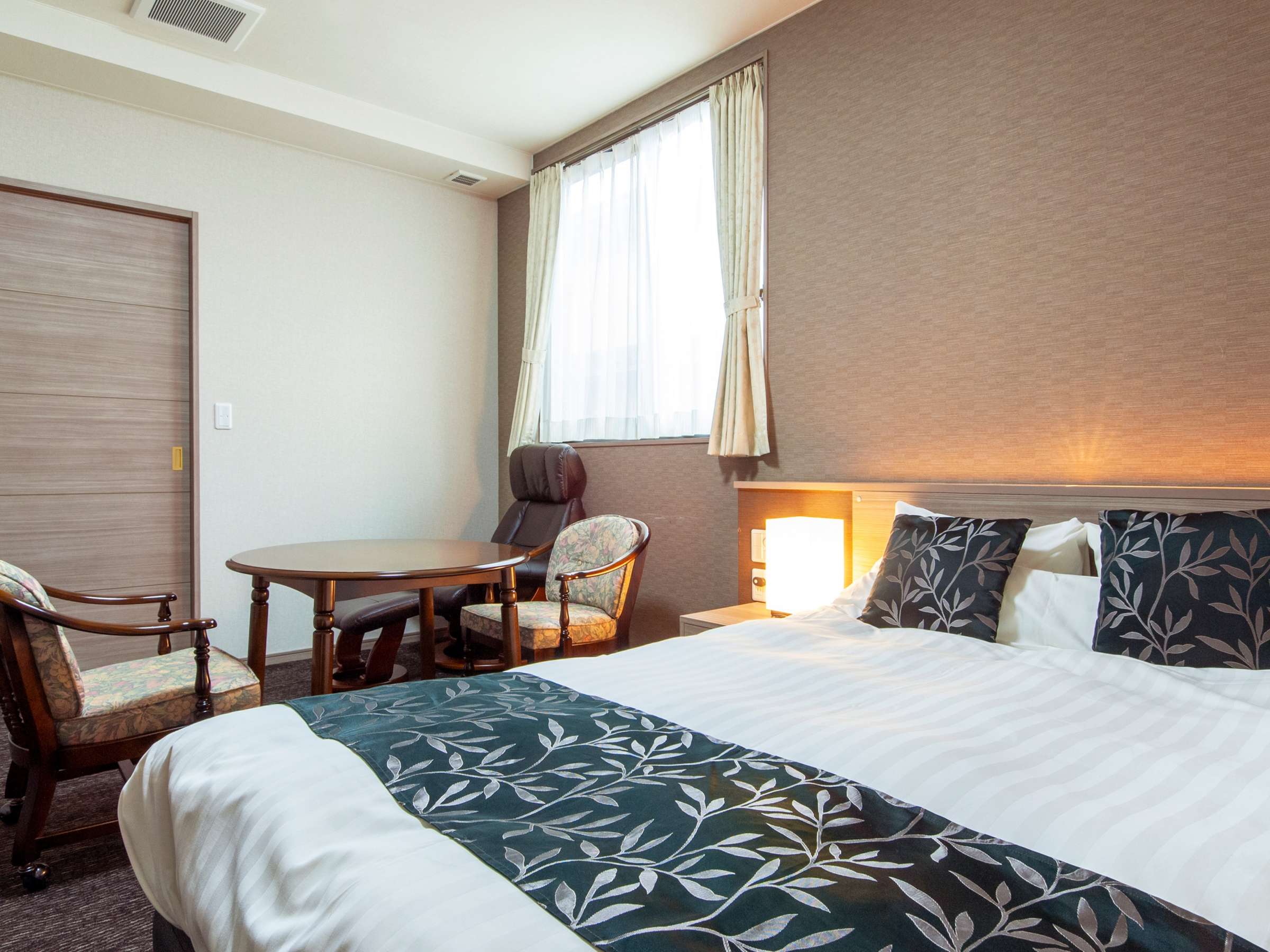 Oyado Yukizumi double guest room with leaf-pattern bed runner, round table and window armchair
