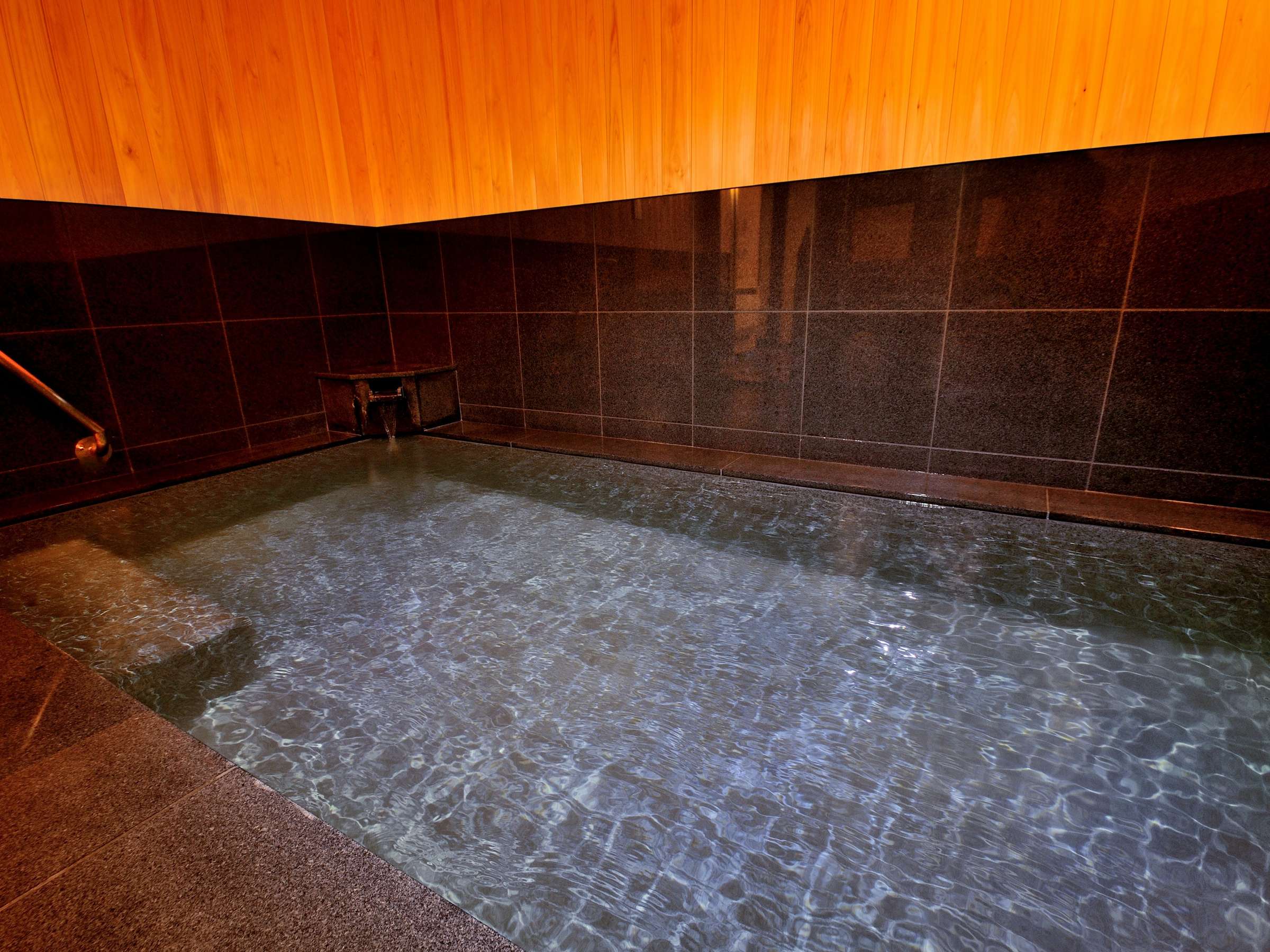 Oyado Yukizumi indoor onsen bath wide view with dark granite tiling and clear thermal water