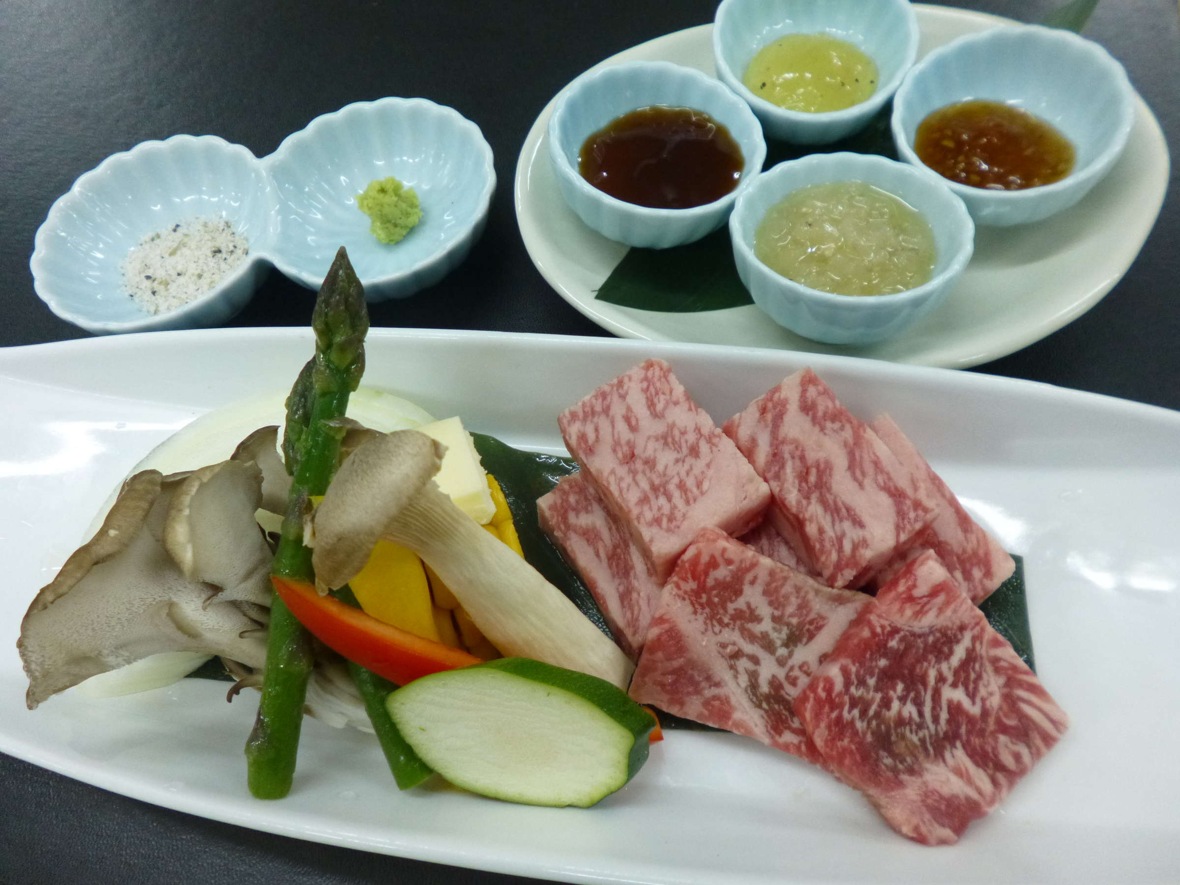 Plated marbled wagyu beef with grilled vegetables and dipping sauces served at Shirafuneso Shintaku Ryokan, Shirahone Onsen