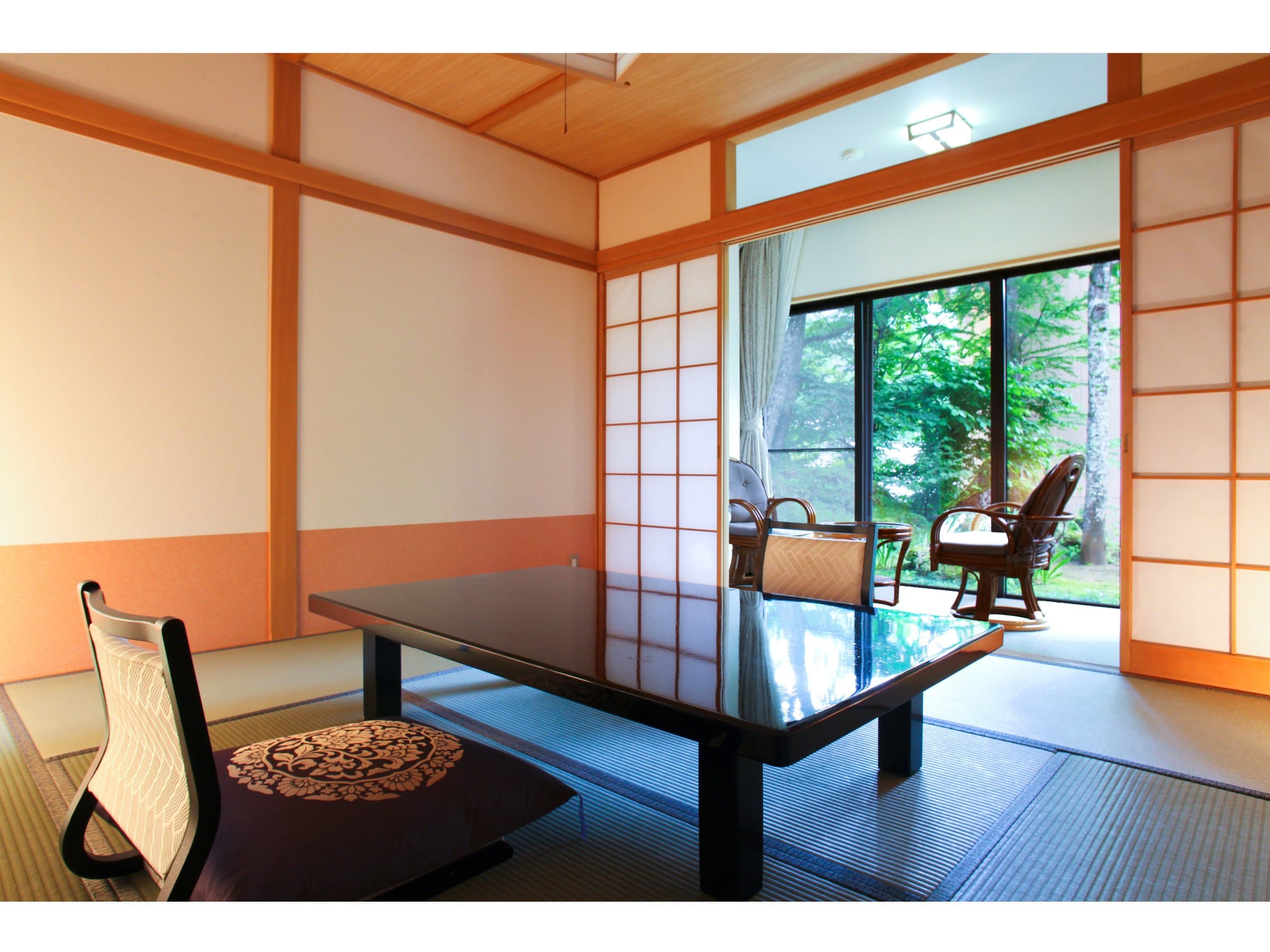 Tatami guest room with low lacquer table and floor seats at Shirafuneso Shintaku Ryokan, opening onto a green garden view in Shirahone Onsen