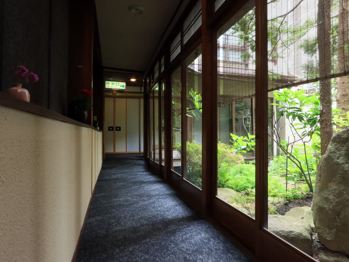 Wood-framed glass corridor overlooking an inner stone garden at Ryokan Tanabe in Takayama