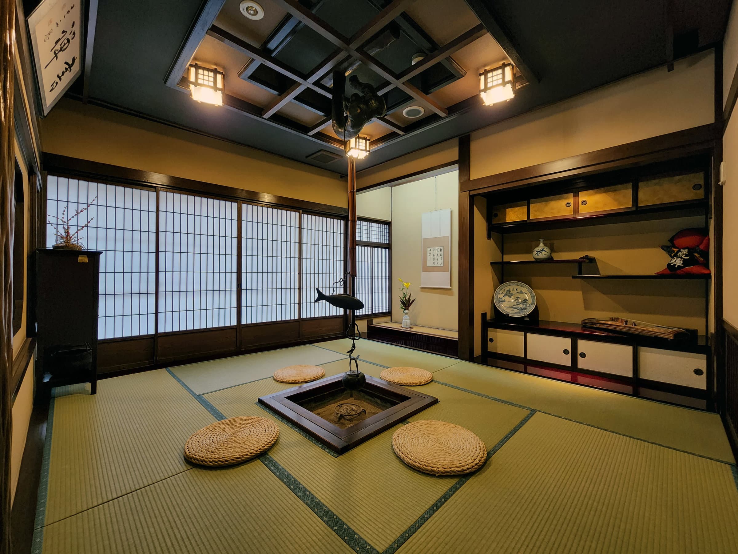 Traditional irori sunken hearth room with tatami, alcove display and hanging lanterns at Ryokan Tanabe