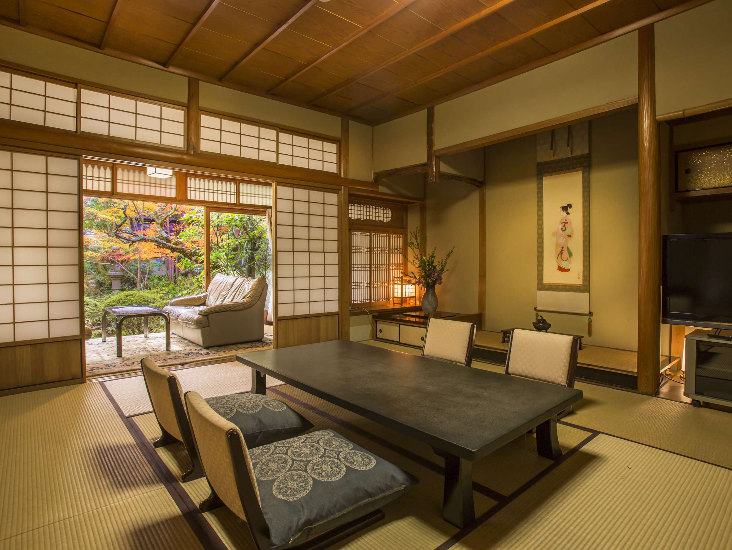 Premium tatami guest room at Hashinoya Bekkan Ransui with a hanging bijinga scroll in the tokonoma, low table, floor chairs and a garden-view sitting alcove