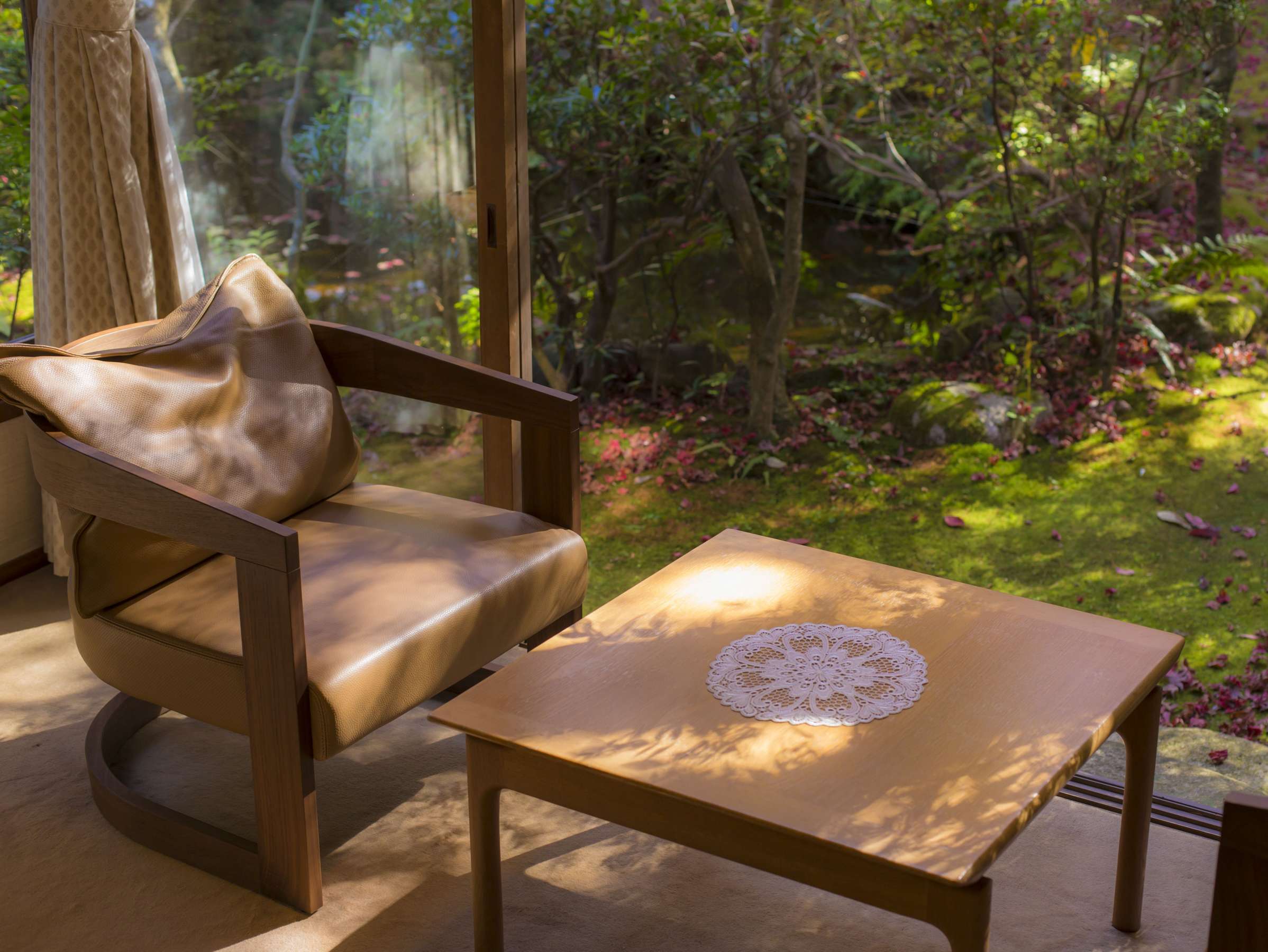 Tatami guest room at Hashinoya Bekkan Ransui opening through shoji and glass onto a private maple garden in autumn colour, with two armchairs by the window