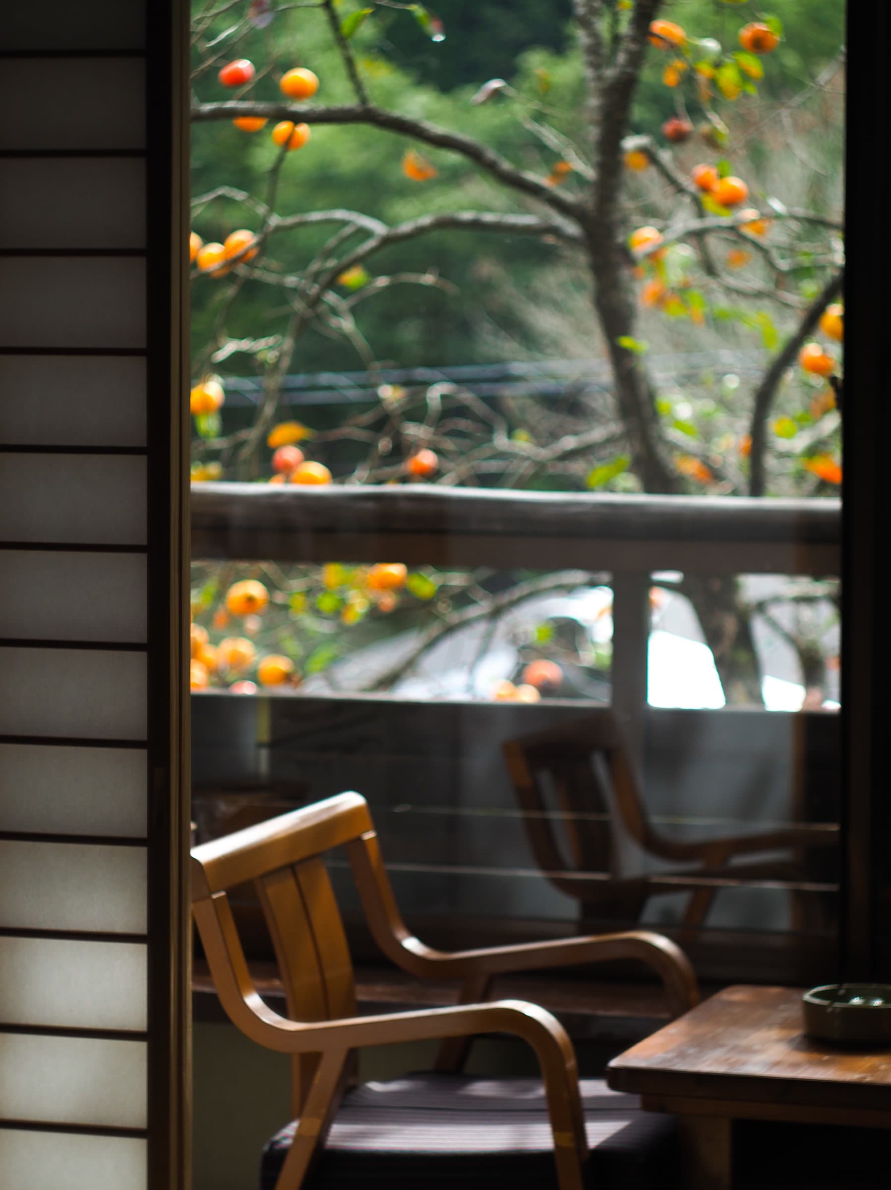Quiet sitting nook at Wafu Ryokan Misato with chairs framing a window of autumn foliage