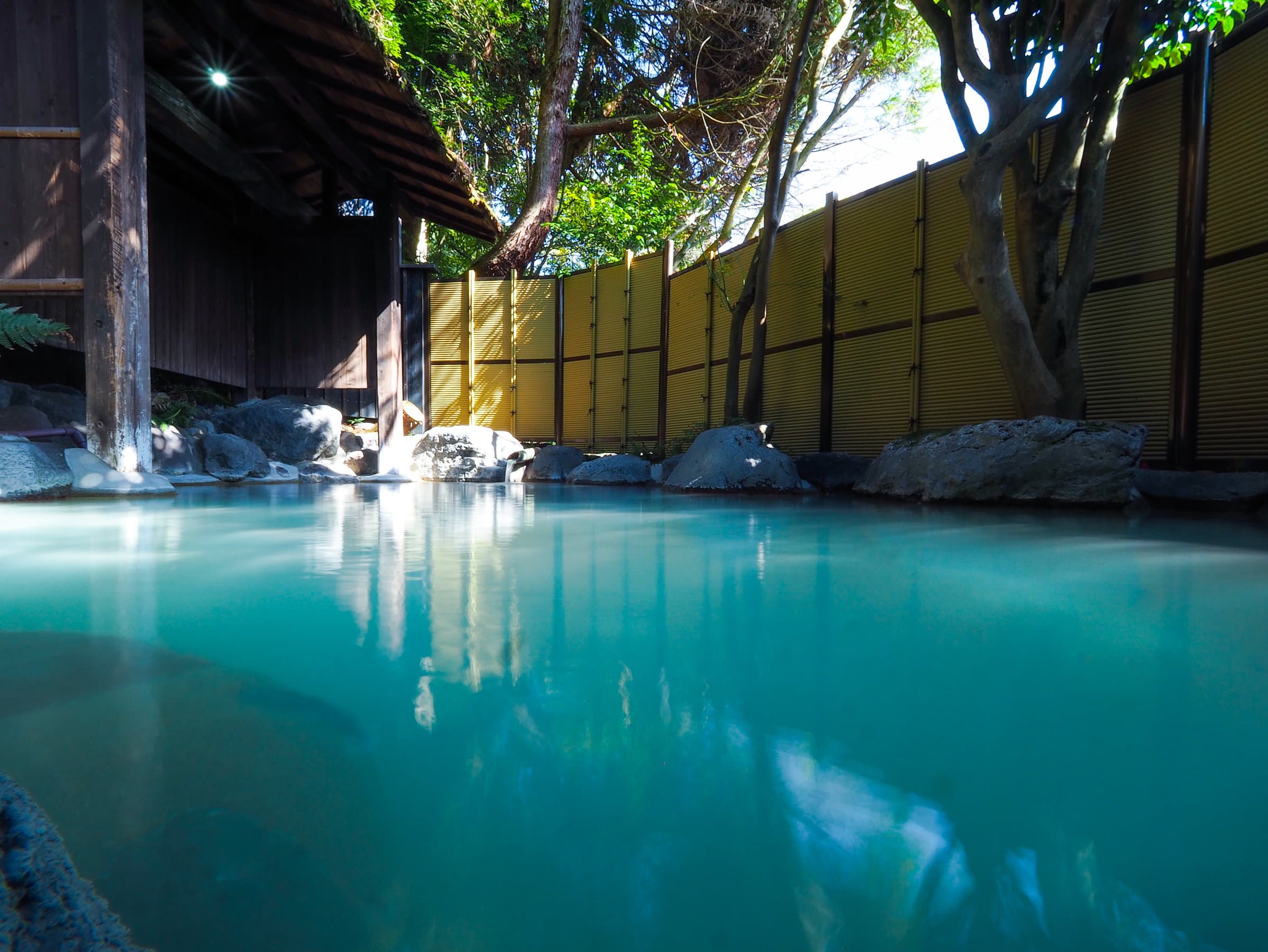 Daytime open-air rotenburo at Wafu Ryokan Misato set among natural stone and greenery
