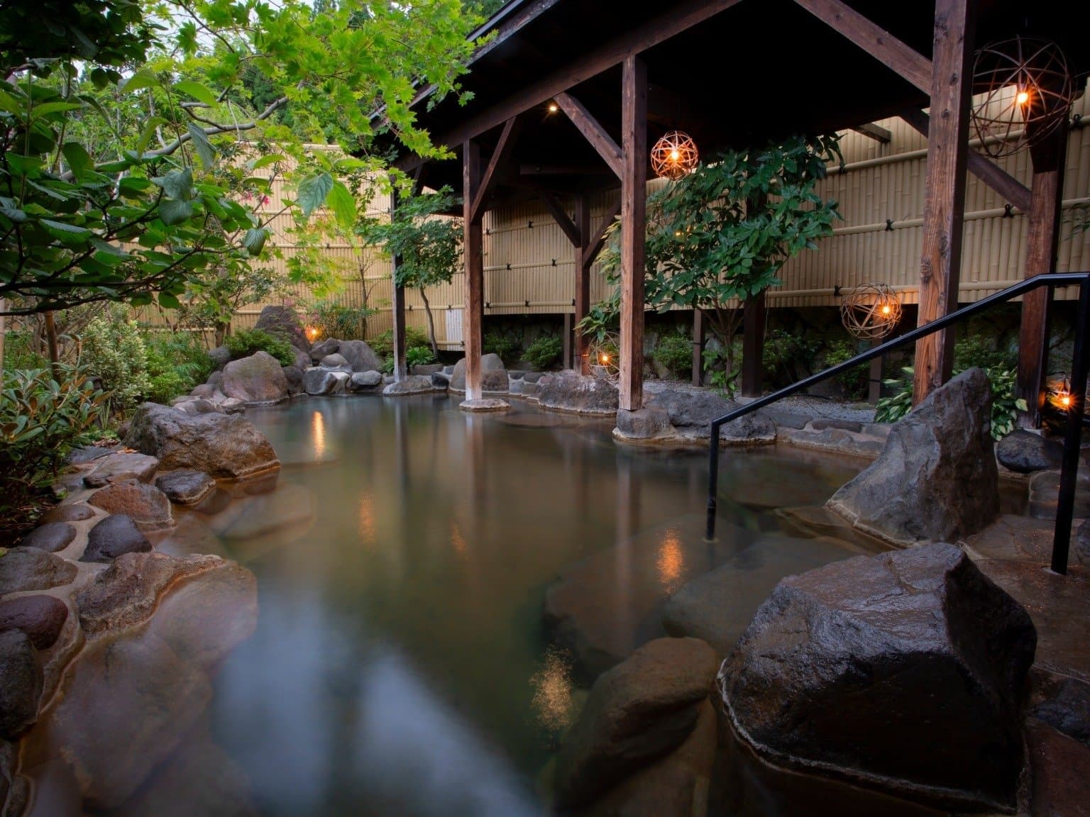 Lantern-lit open-air bath at Wafu Ryokan Misato beside a hydrangea garden at dusk