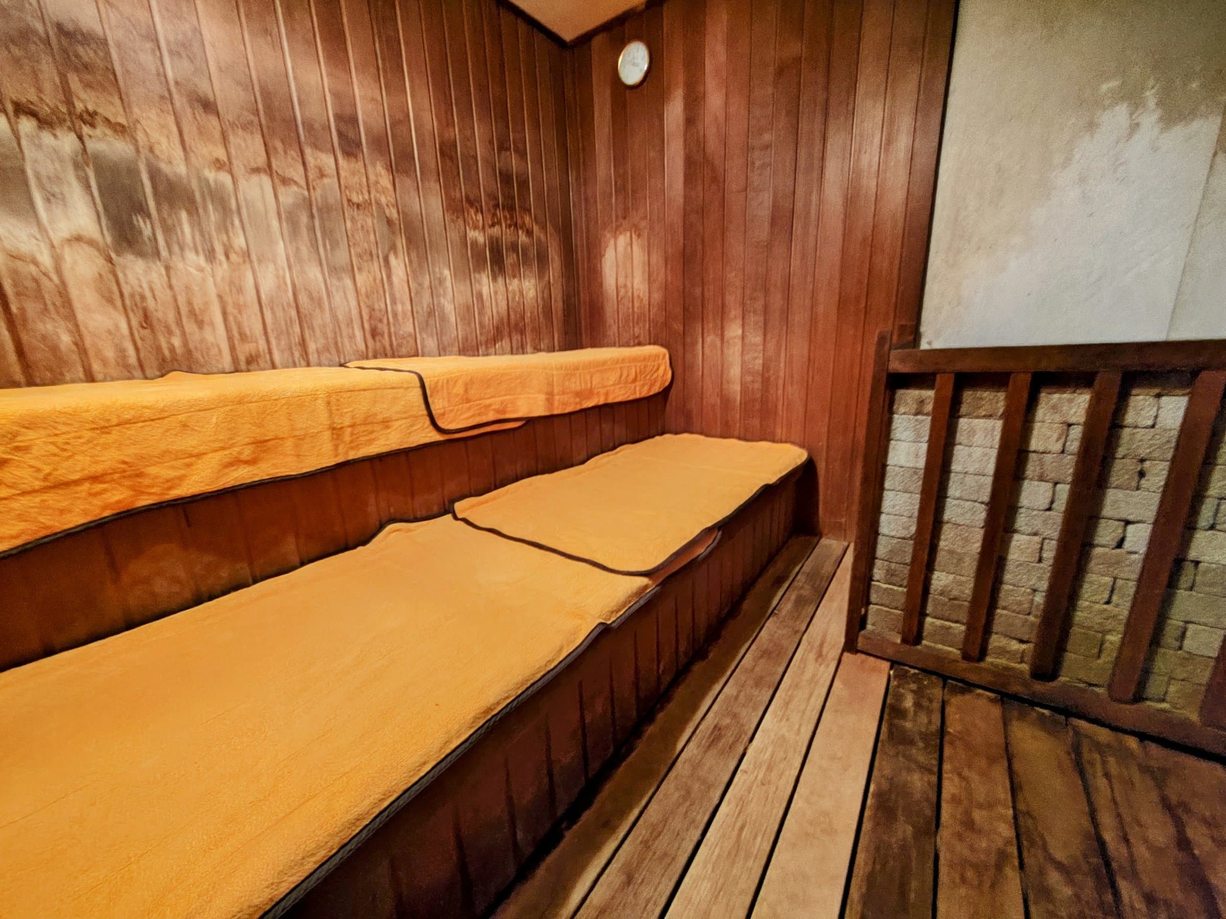 Cedar-walled dry sauna with tiered benches and amber towels at Hotel Spax Kusatsu