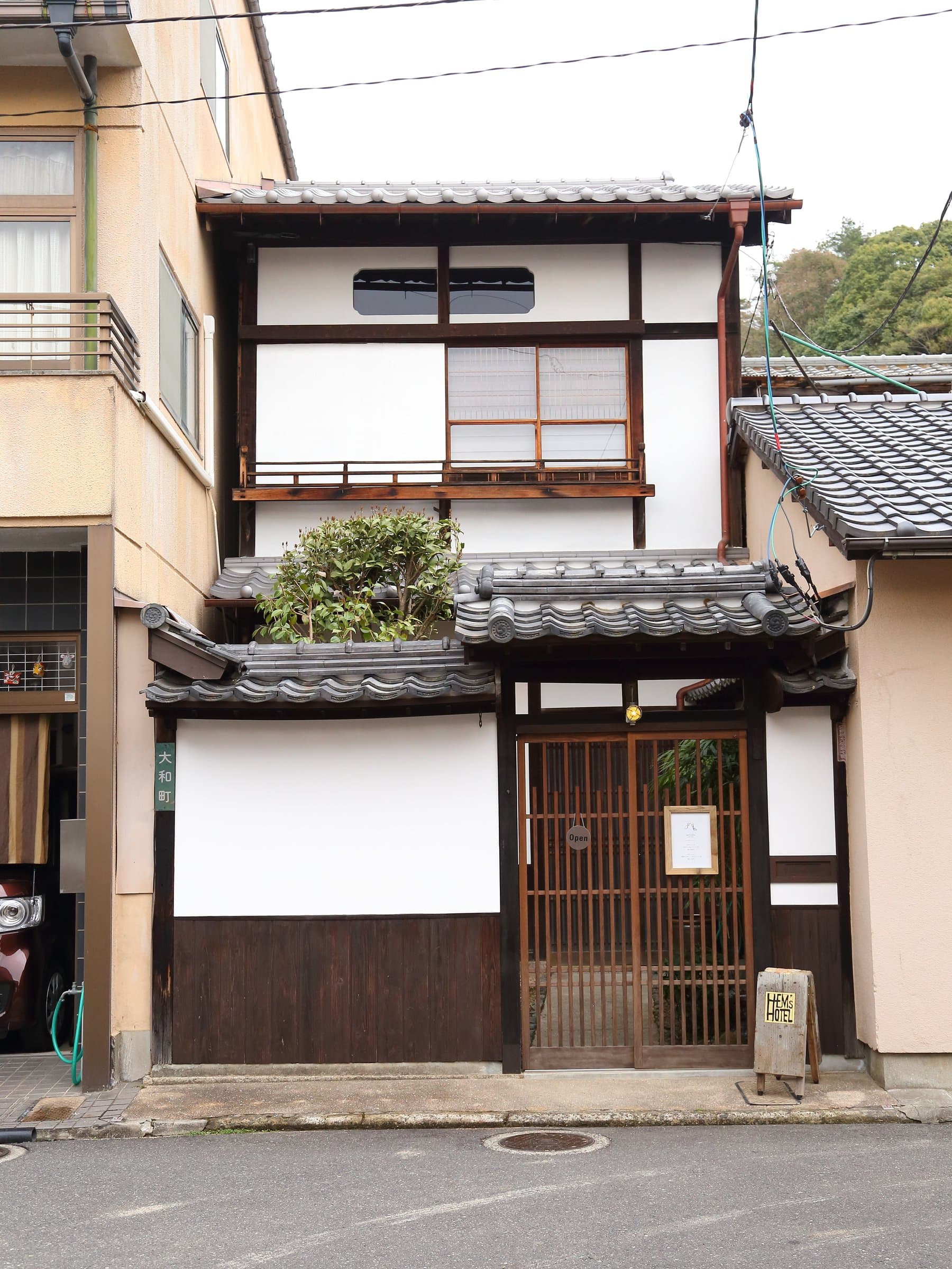 Hem's Hotel restored machiya townhouse exterior with tiled roof and wooden lattice door on Miyajima island