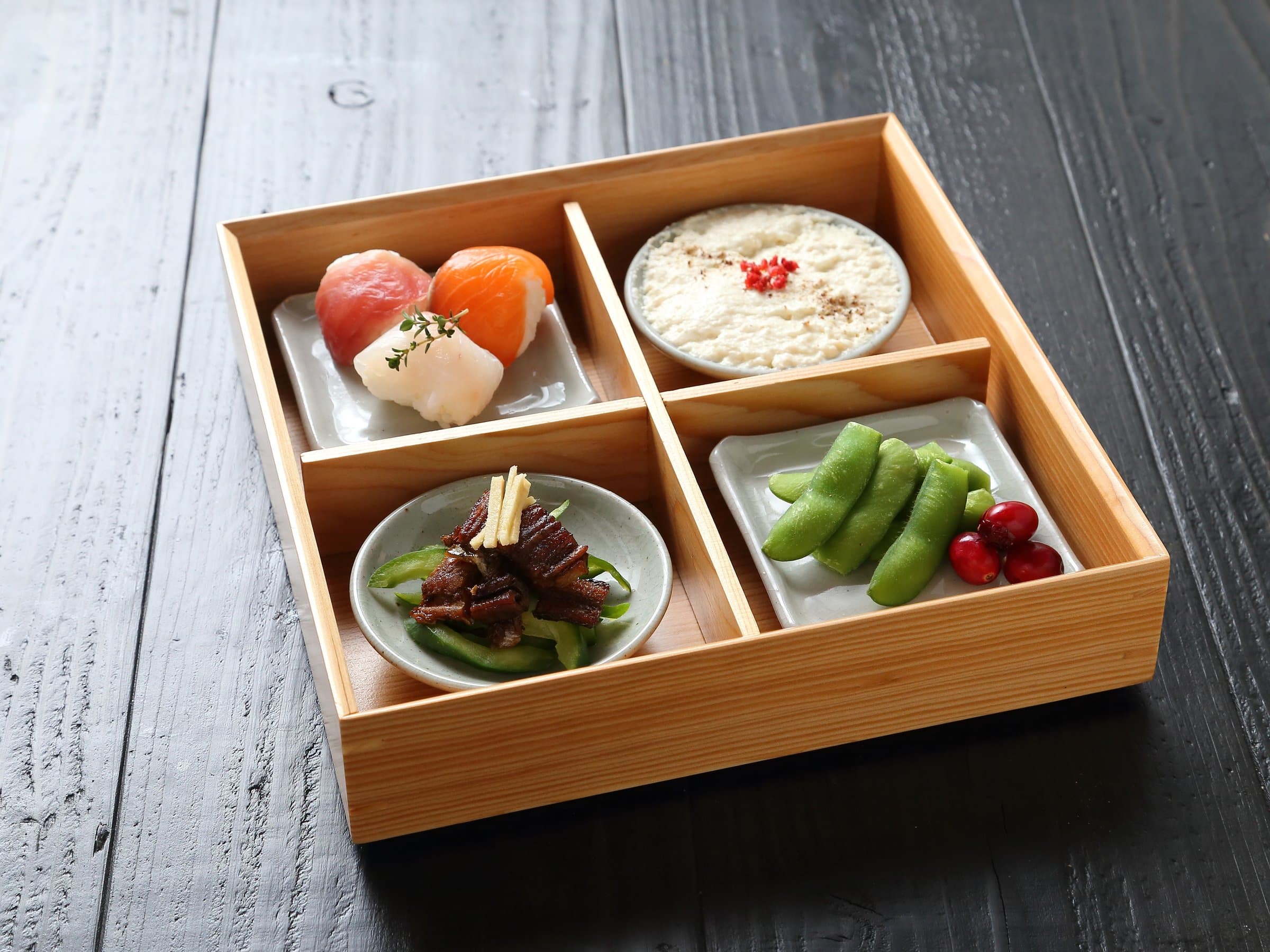 Wooden compartment bento box of sushi, tofu mousse, edamame and simmered vegetables served at Hem's Hotel, Miyajima