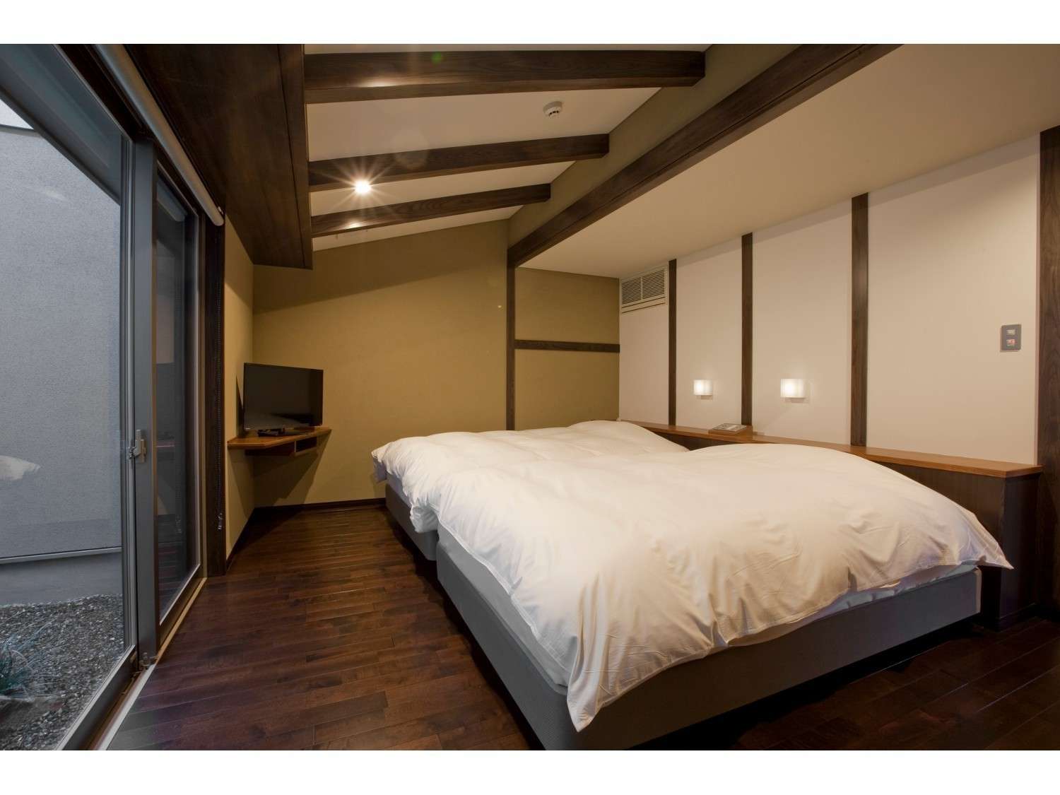 Western-style twin bedroom with white duvets, exposed timber ceiling beams and dark wood flooring, Amane Resort GAHAMA, Beppu Onsen