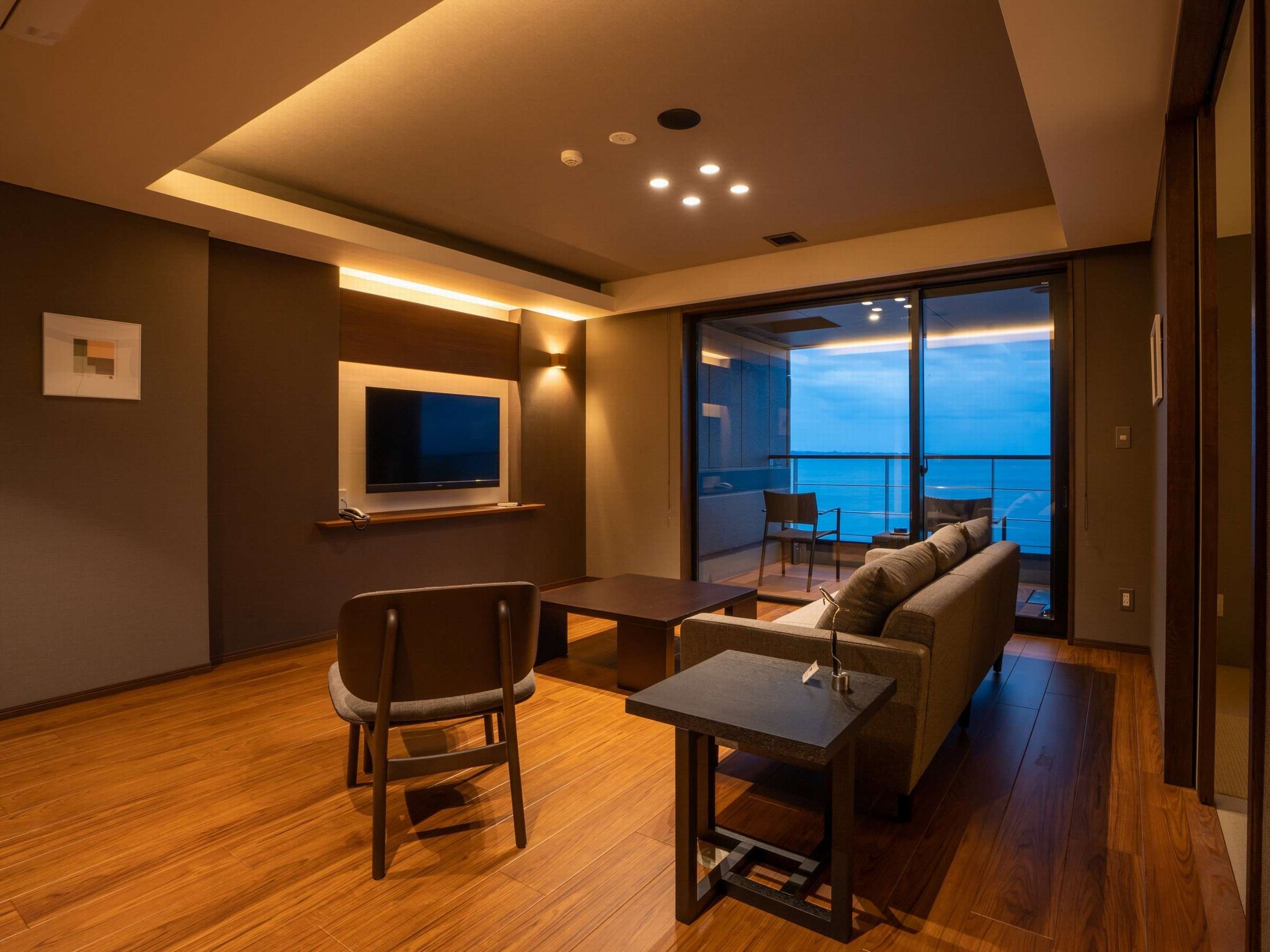 Guest room living area at dusk with sofa facing a balcony and ocean view, Amane Resort GAHAMA, Beppu Onsen