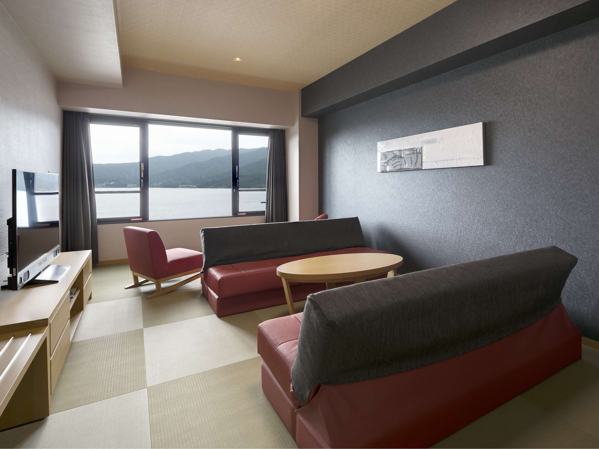 Suite living room with tatami flooring, red lounge chairs and a sea-facing window over the Seto Inland Sea