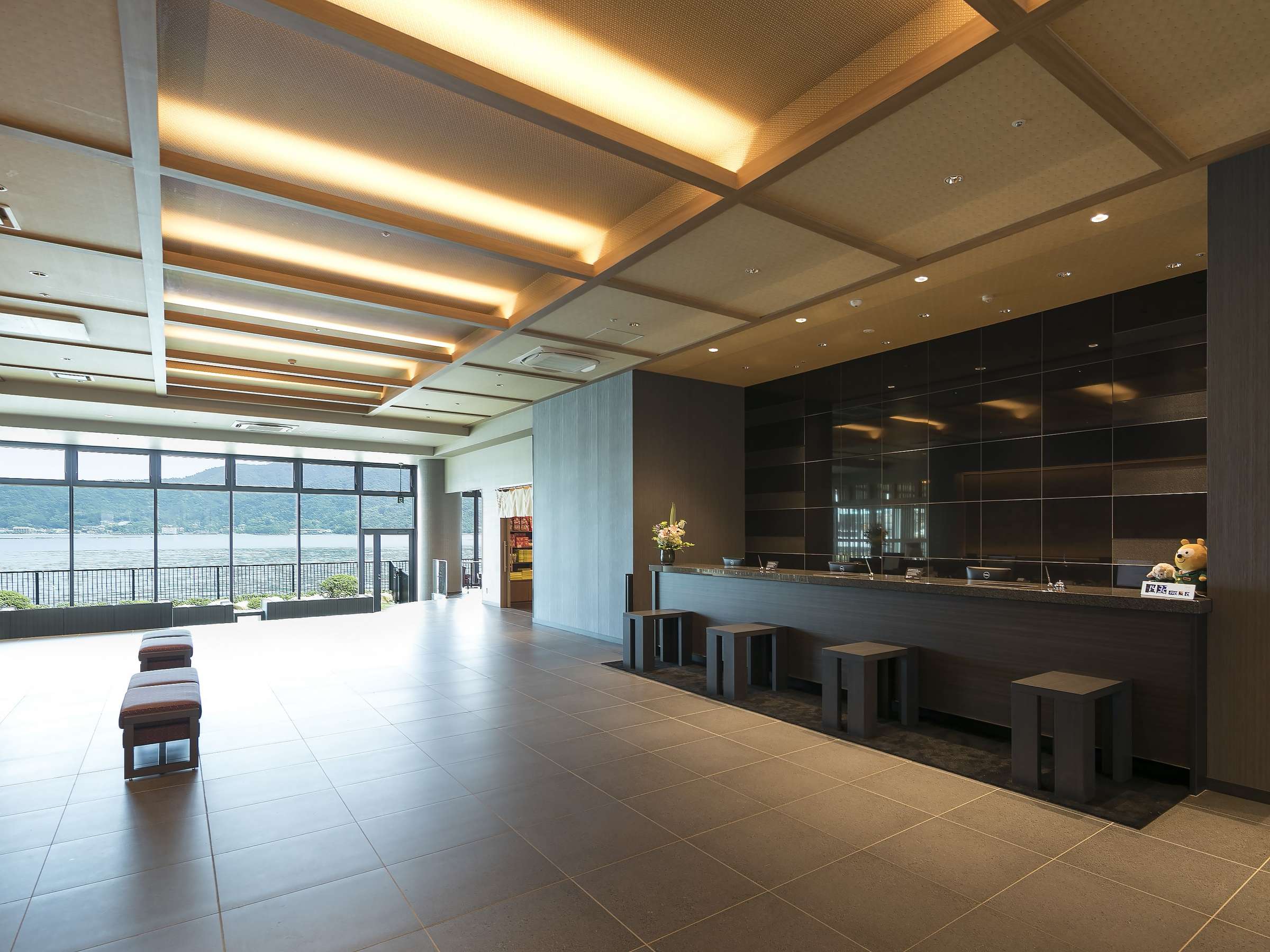 Spacious hotel lobby and front desk with wood-panelled ceiling and sea-view windows